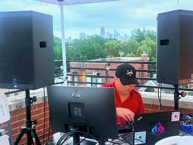 a man with a laptop and speakers on a rooftop in chicago