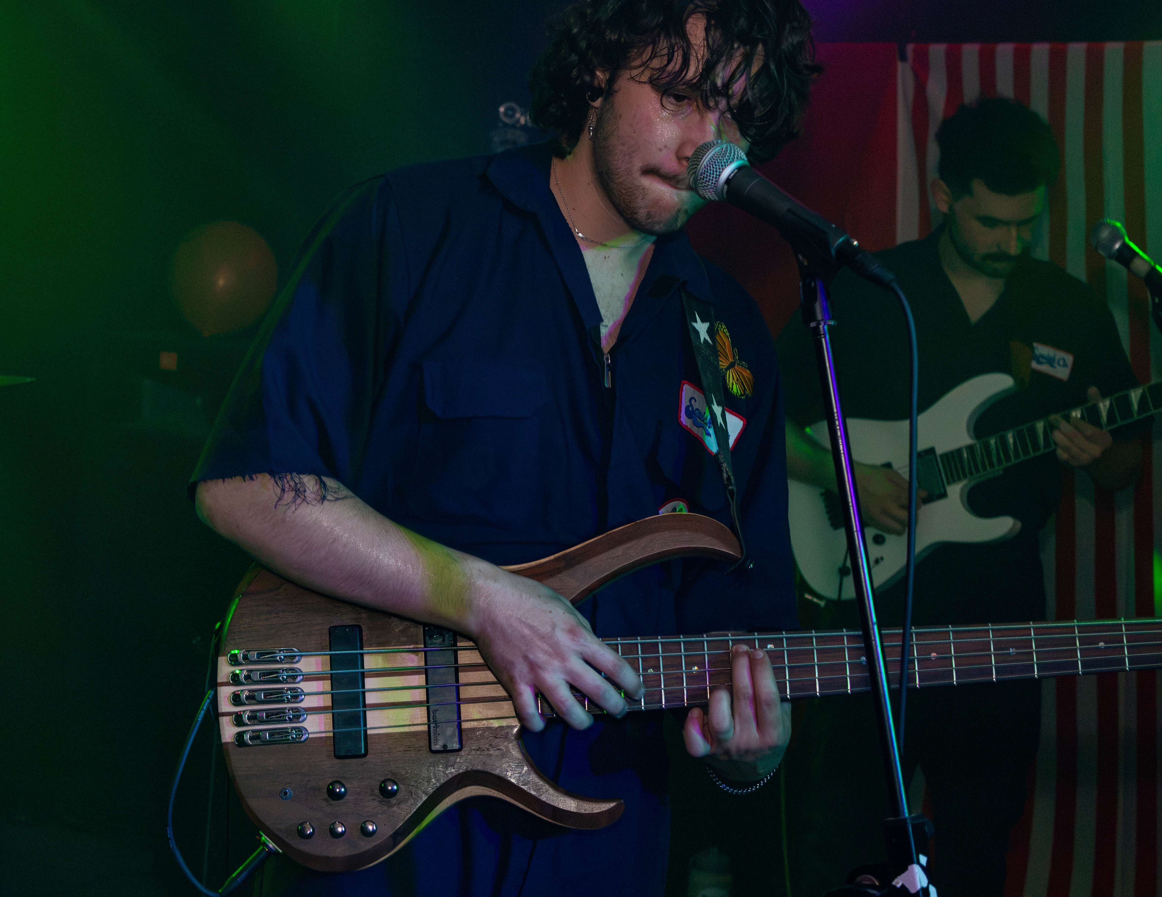 a man playing a bass guitar in front of a microphone