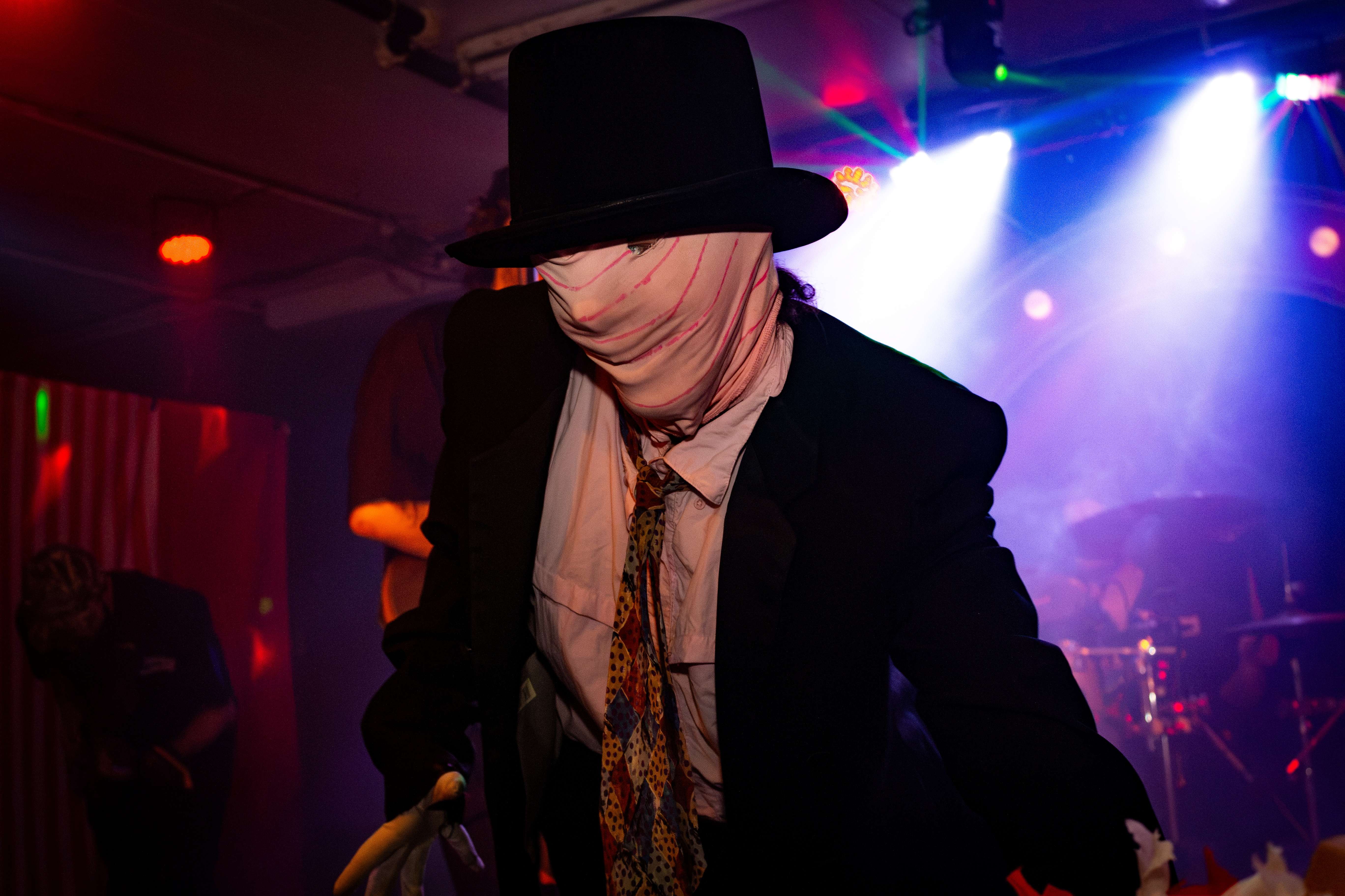 a man in a black suit with a mask on