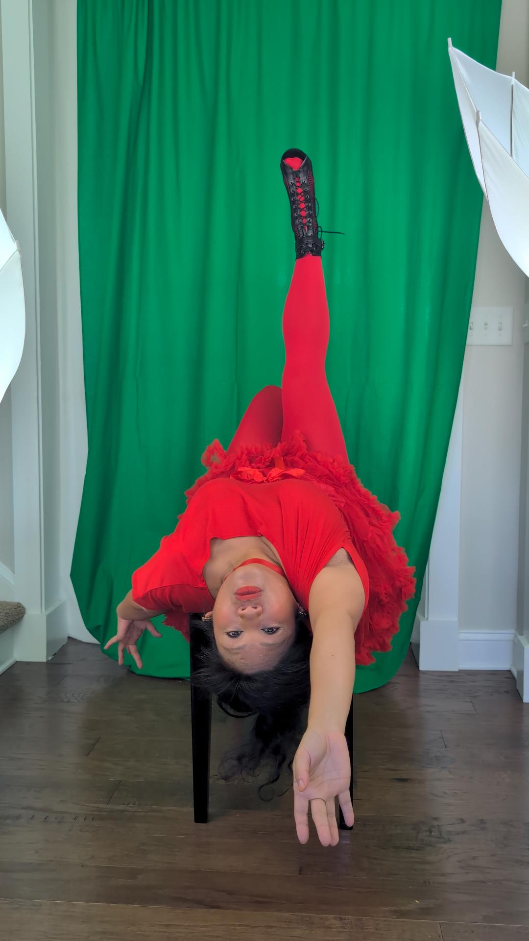 a woman in a red dress is upside down on a chair