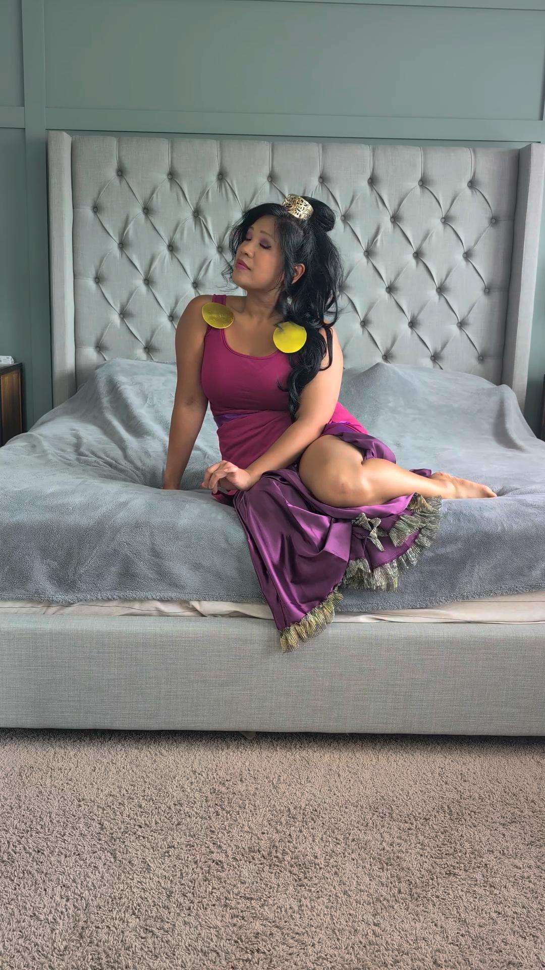 a woman in a purple dress sitting on a bed