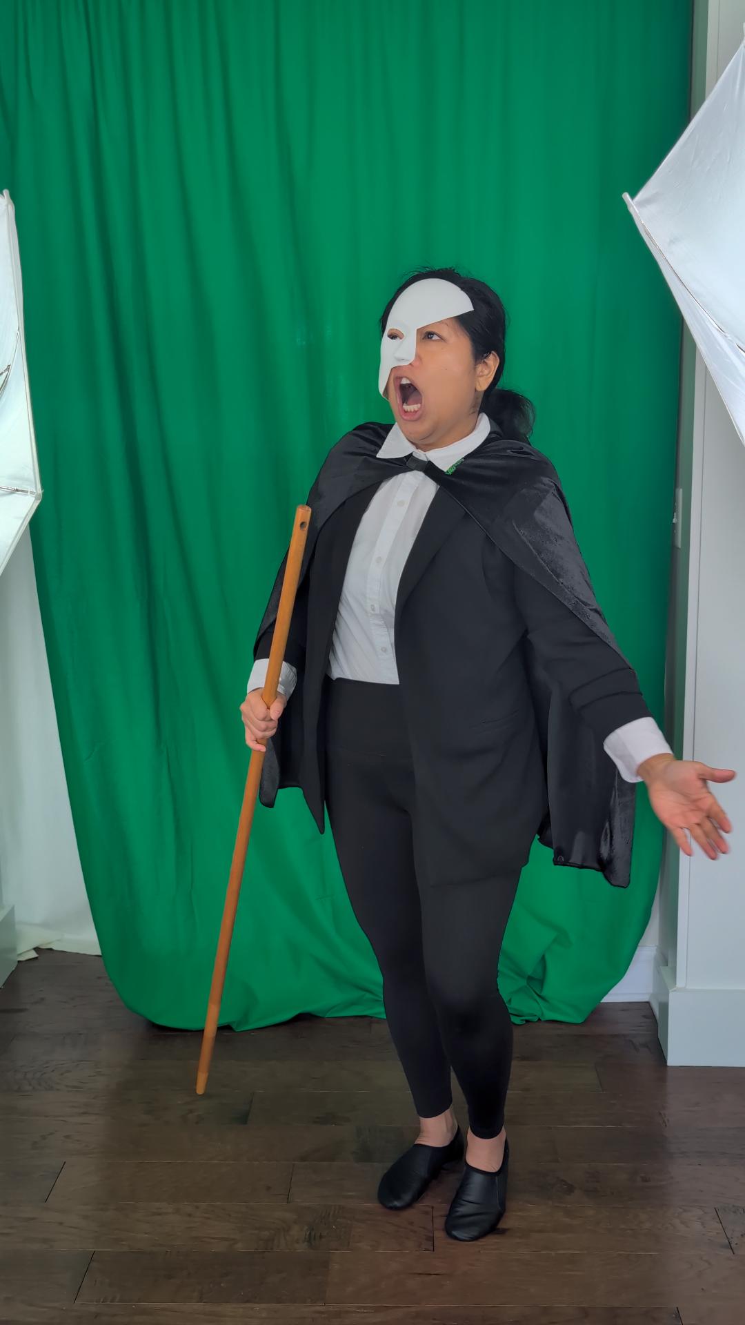 a woman dressed as a phantom in front of a green screen