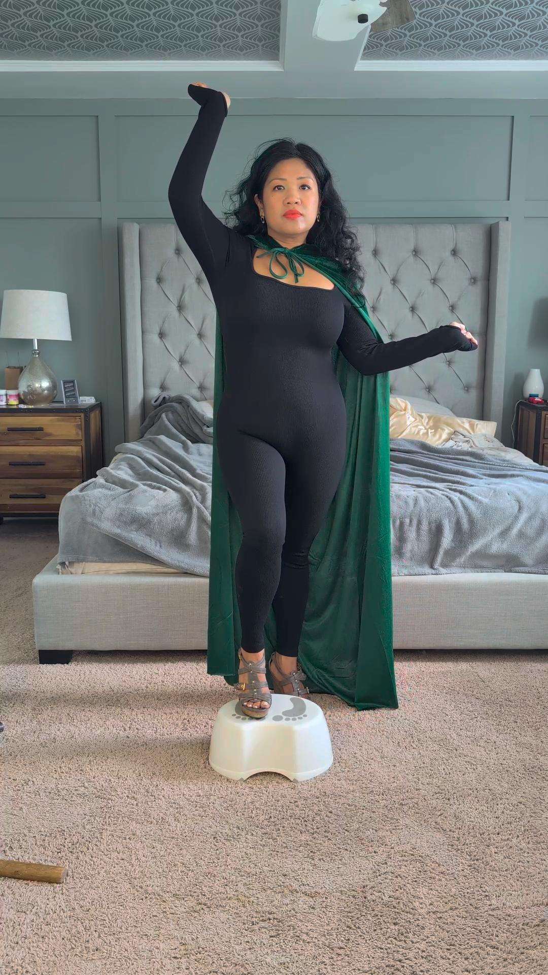 a woman in a green cape standing on a bed