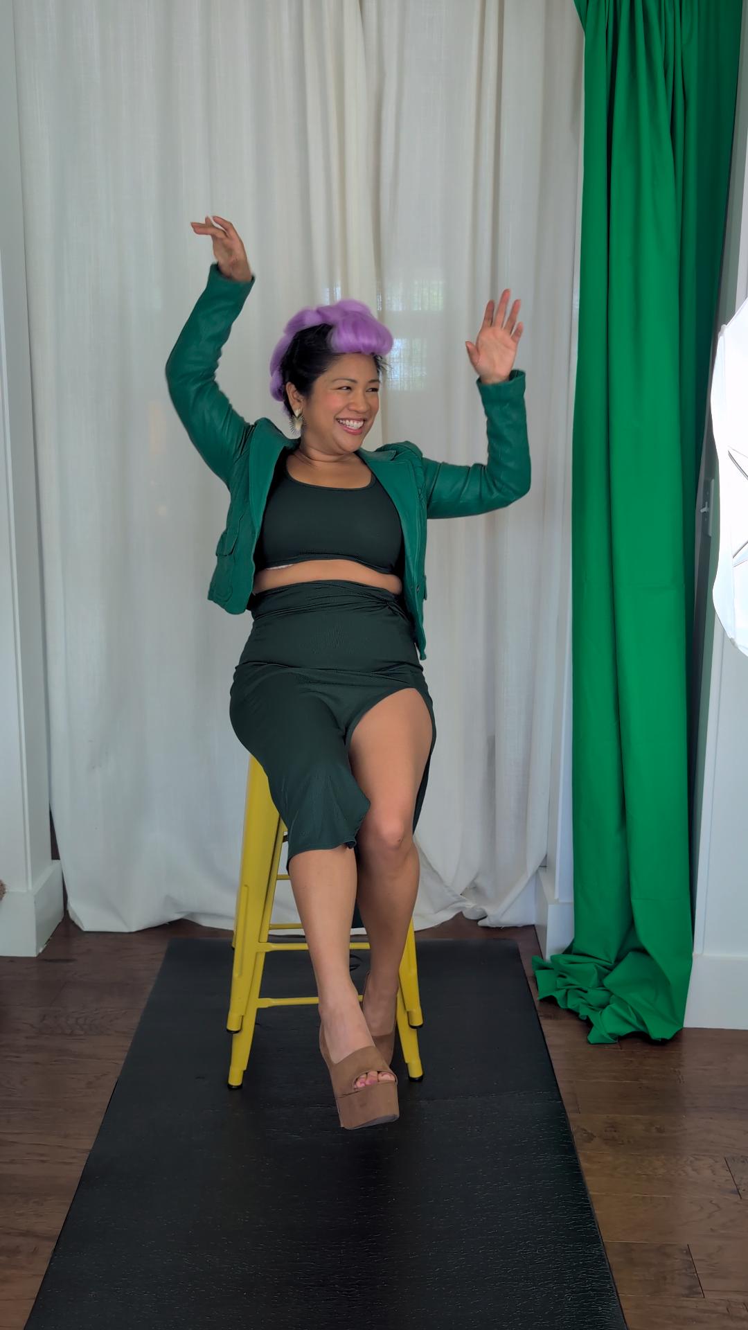 a woman sitting on a stool in front of a green screen