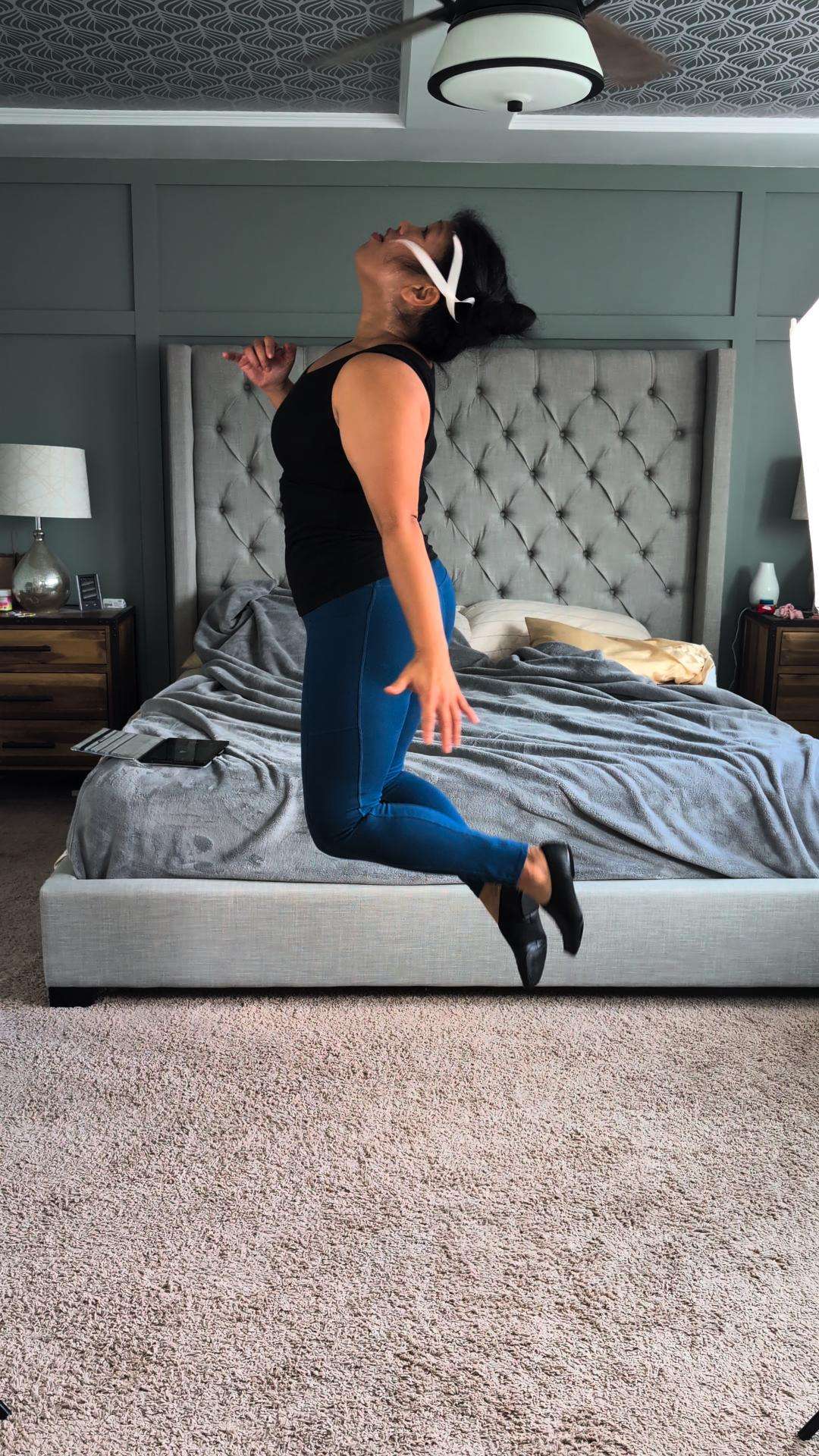 a woman jumping in front of a bed