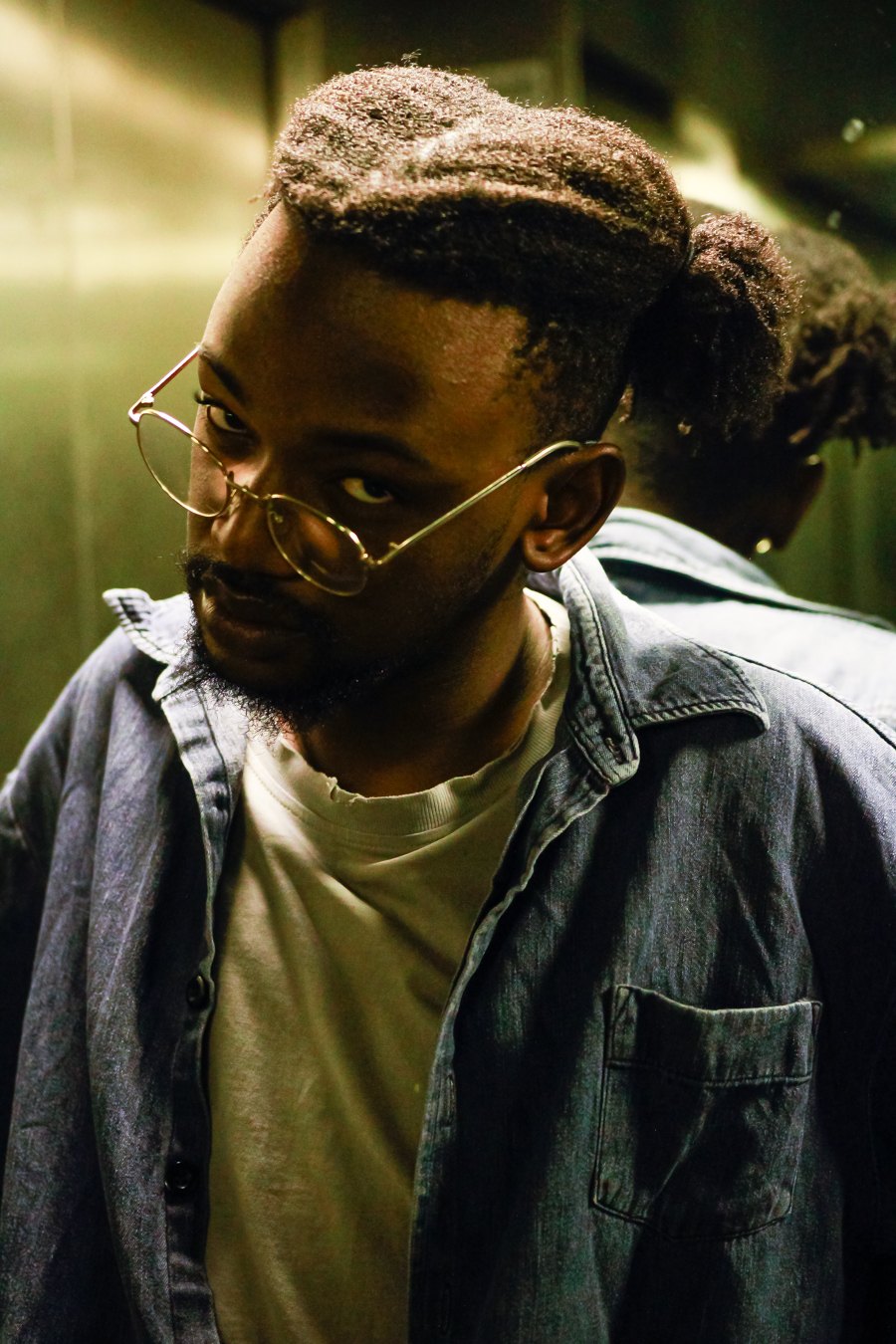 a man in glasses is standing in an elevator