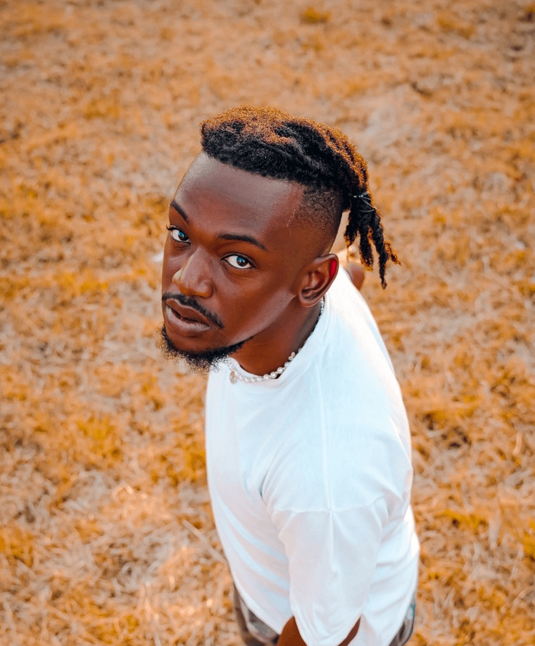 a man with dreadlocks standing in a field