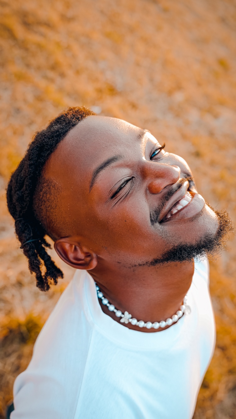 a man with dreadlocks and a white shirt is smiling