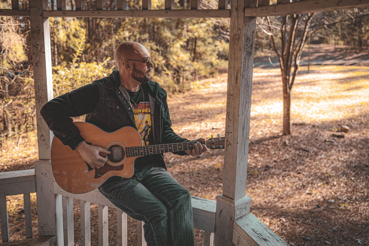 a man playing an acoustic guitar on a gazebo