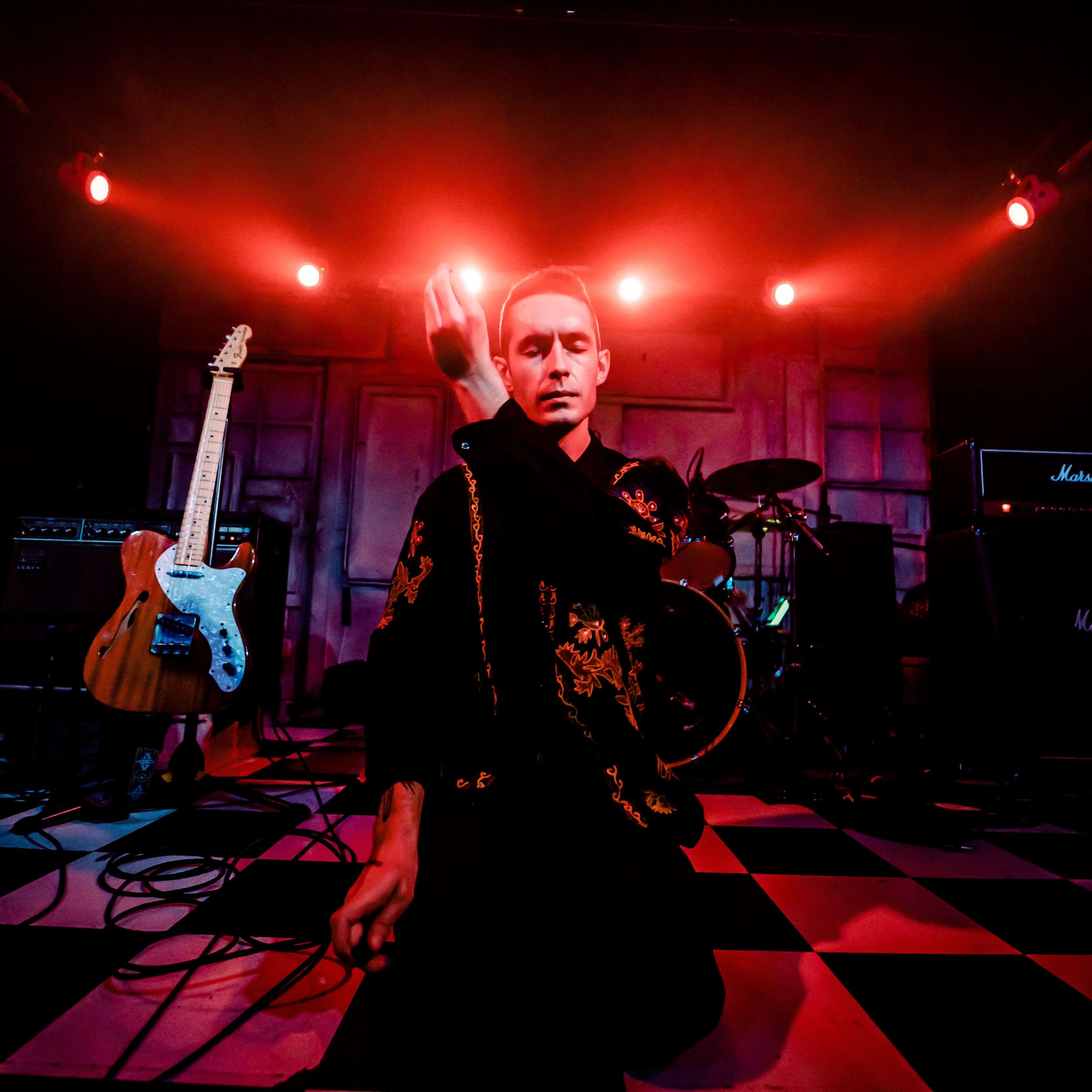 a man sitting on a stage with a guitar