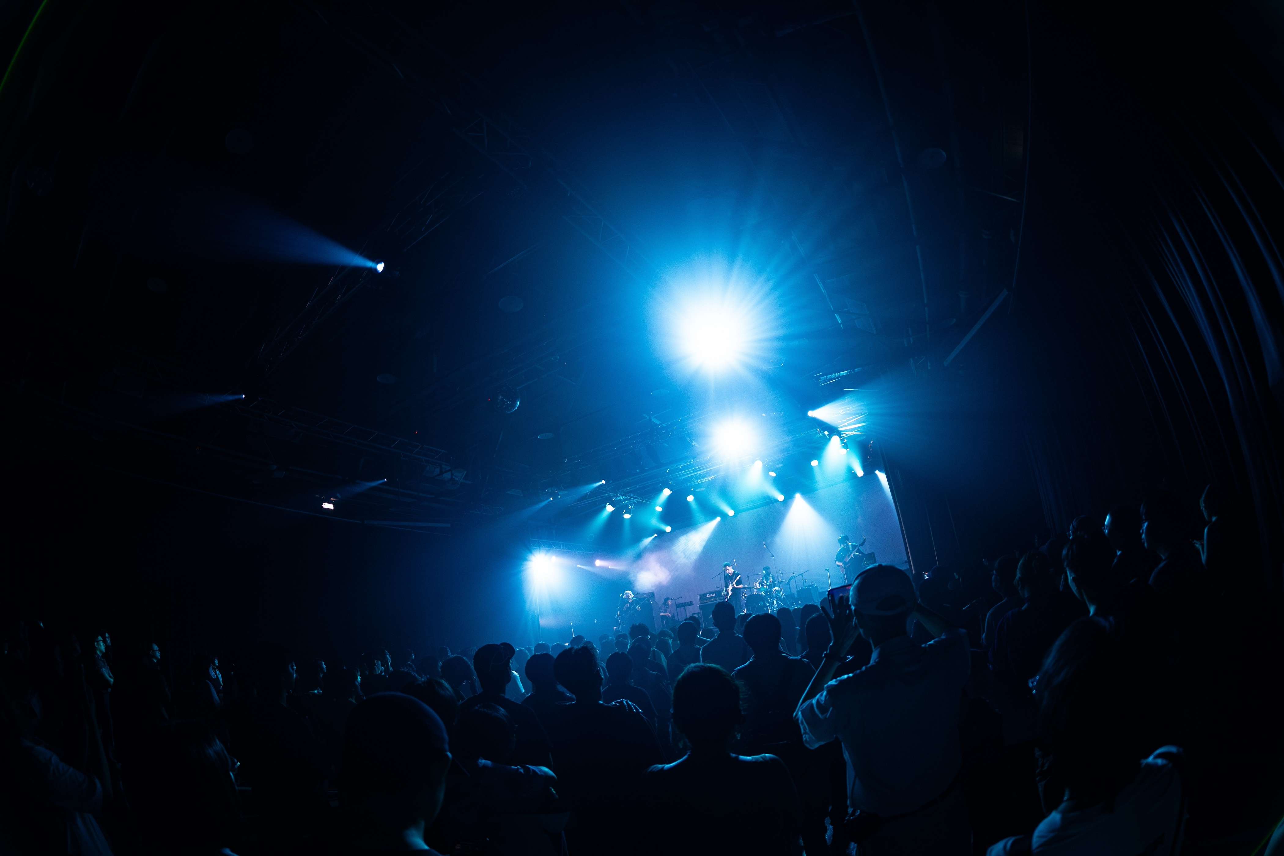 a crowd at a concert with blue lights in the background