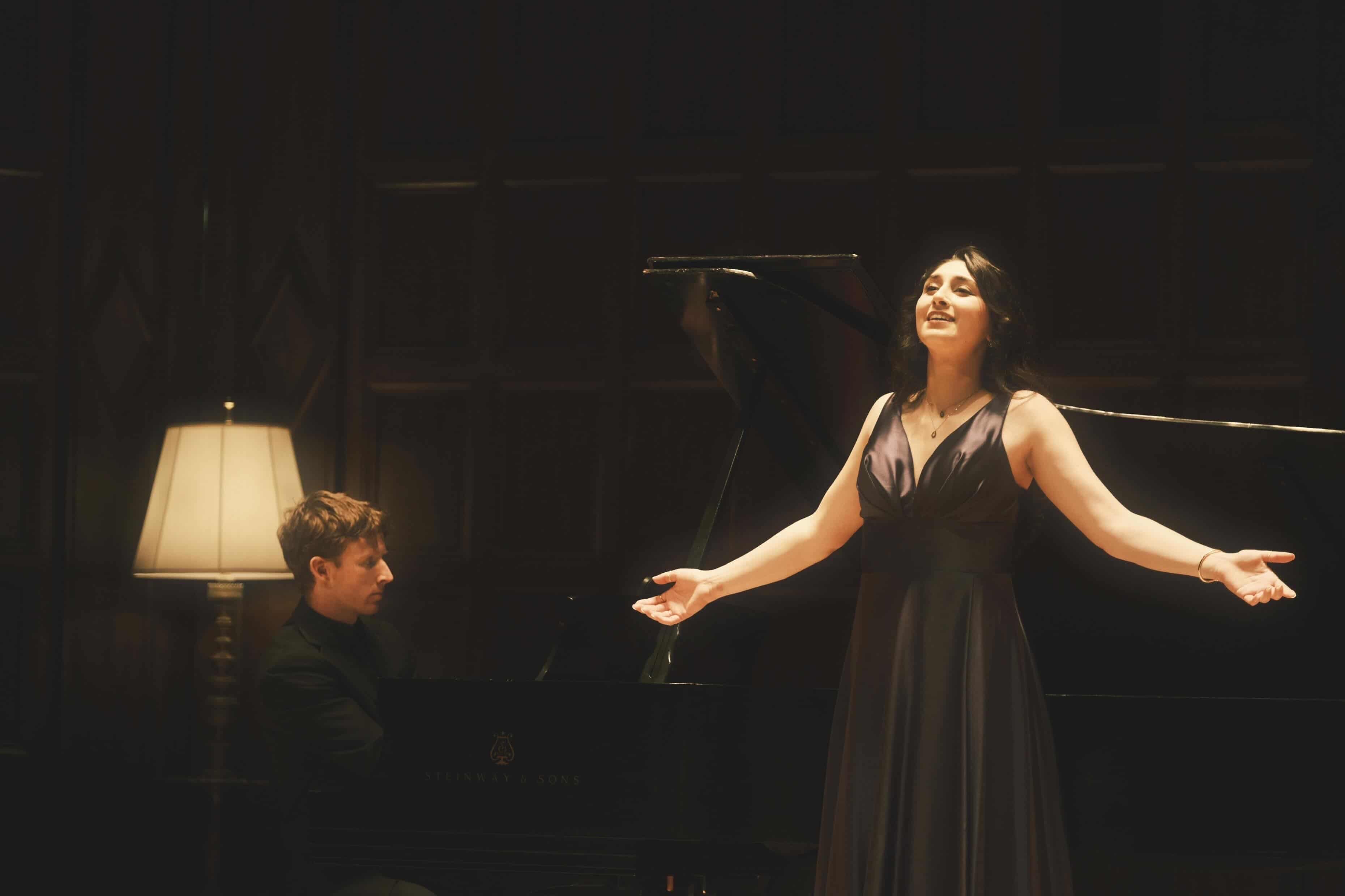 a woman in a long dress is standing next to a piano