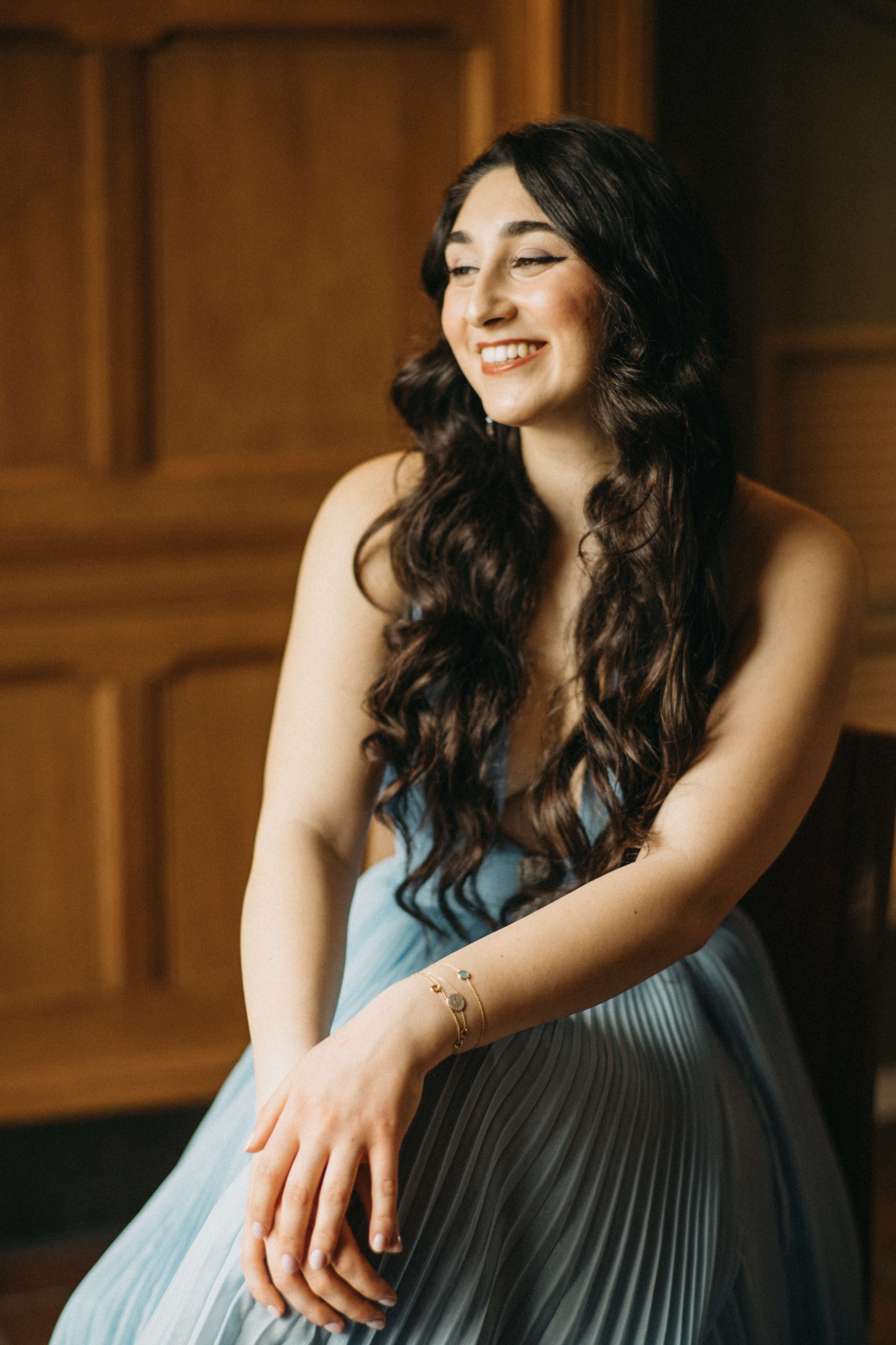 a woman in a blue dress is smiling while sitting on a chair
