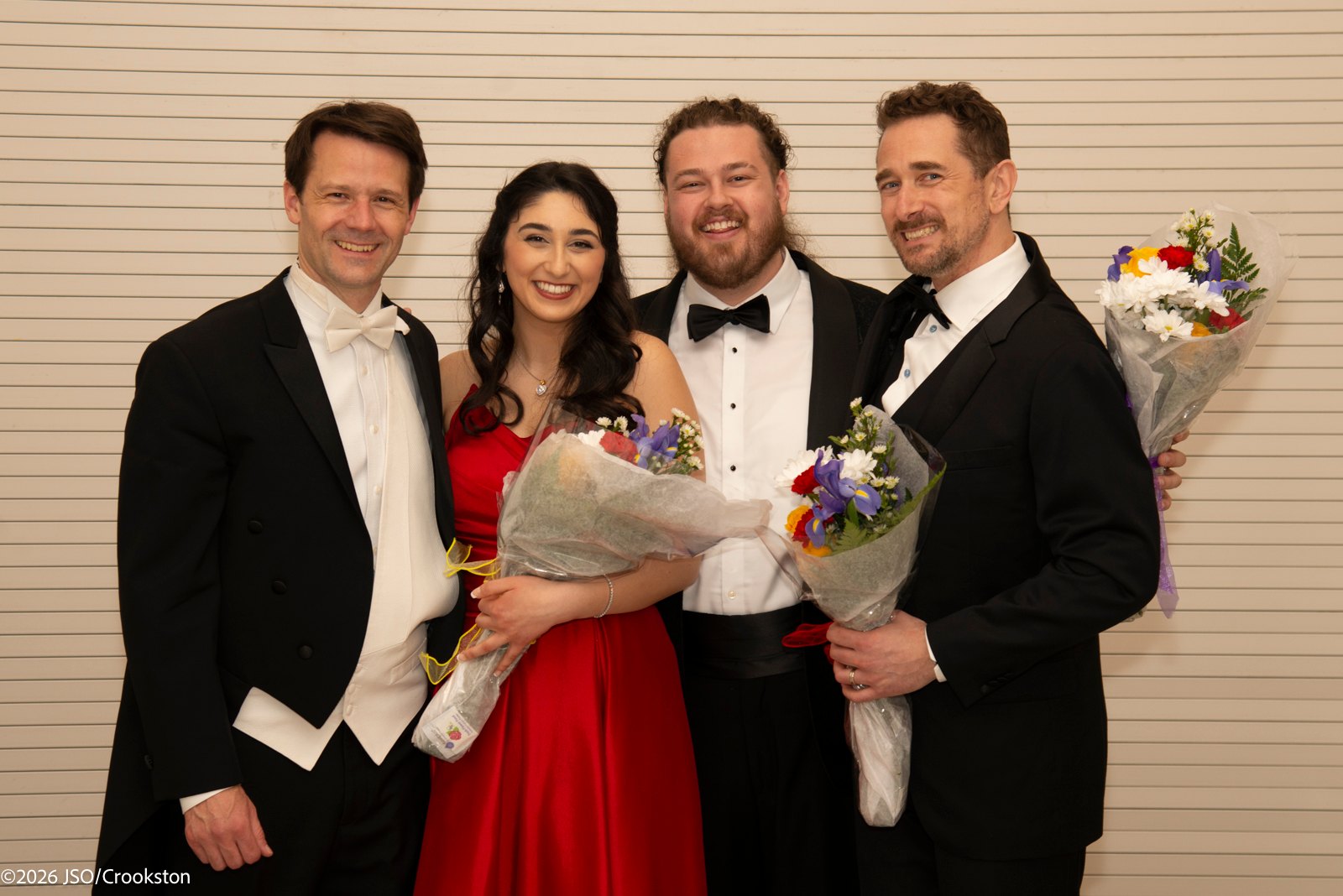 four people in tuxedos posing for a photo