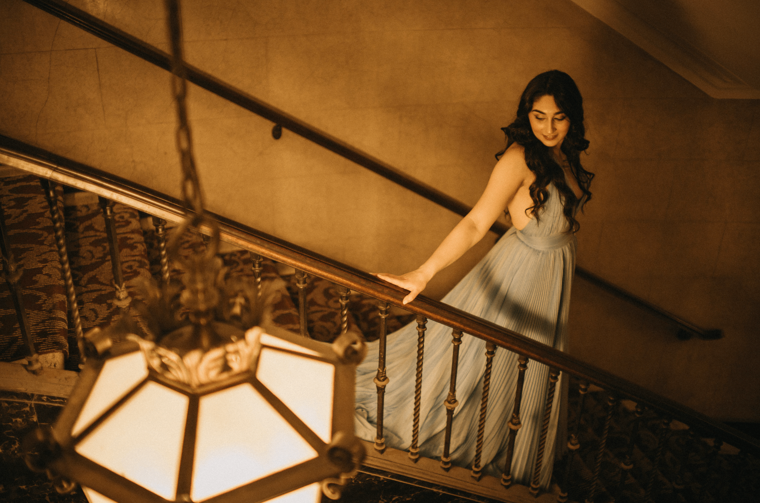 a woman in a blue dress standing on a staircase