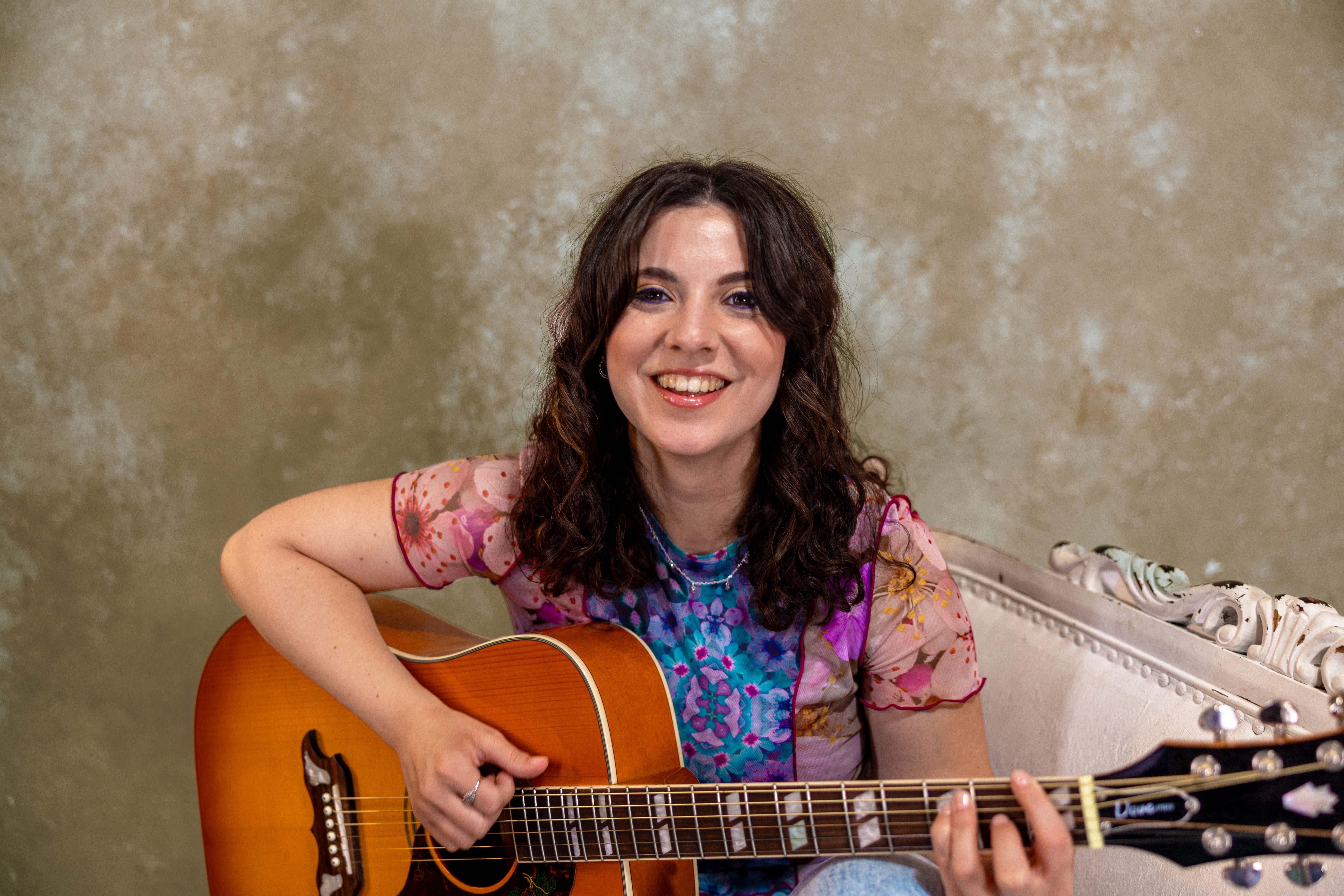 a woman sitting on a couch with an acoustic guitar