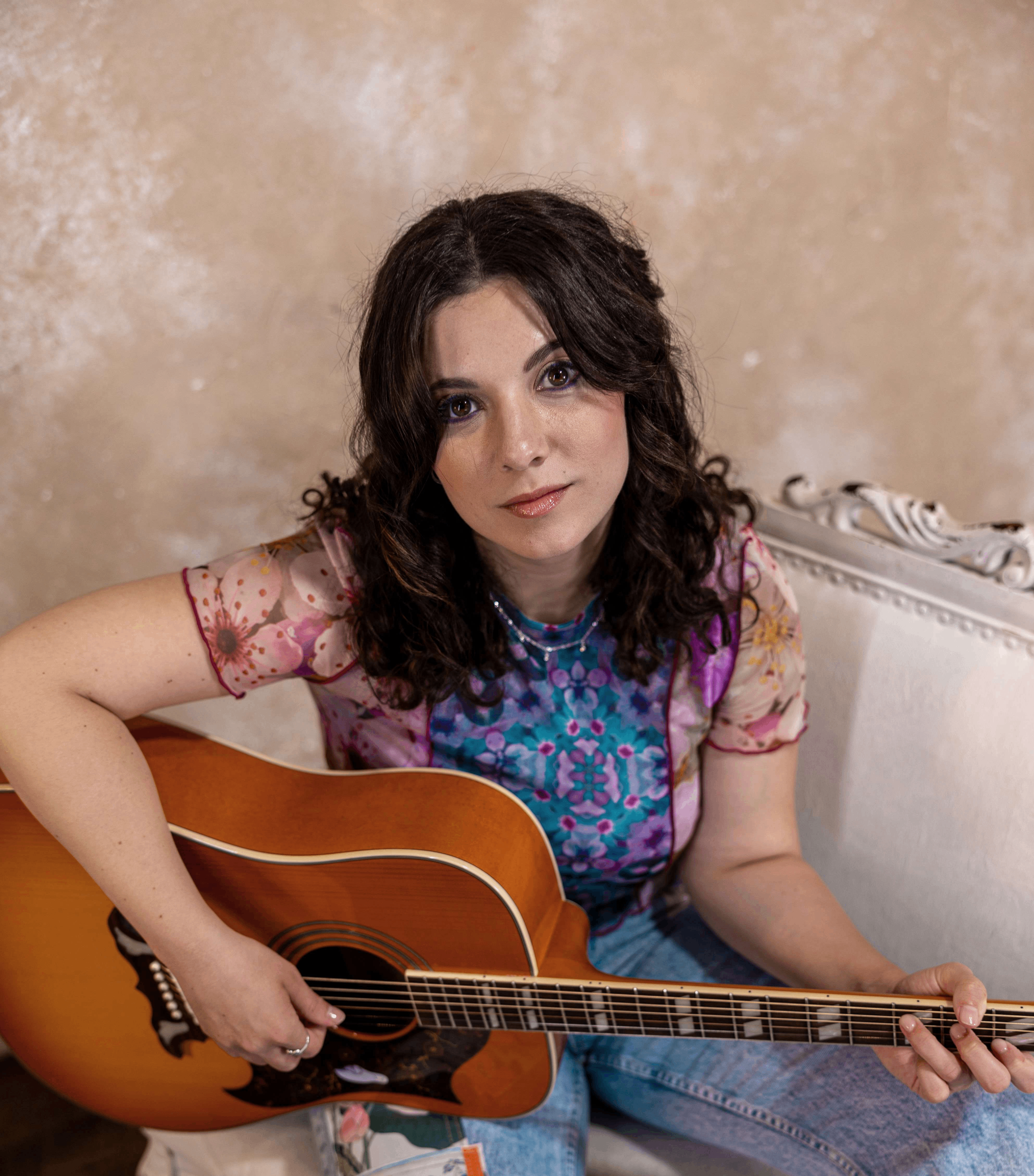 a woman sitting on a couch with an acoustic guitar