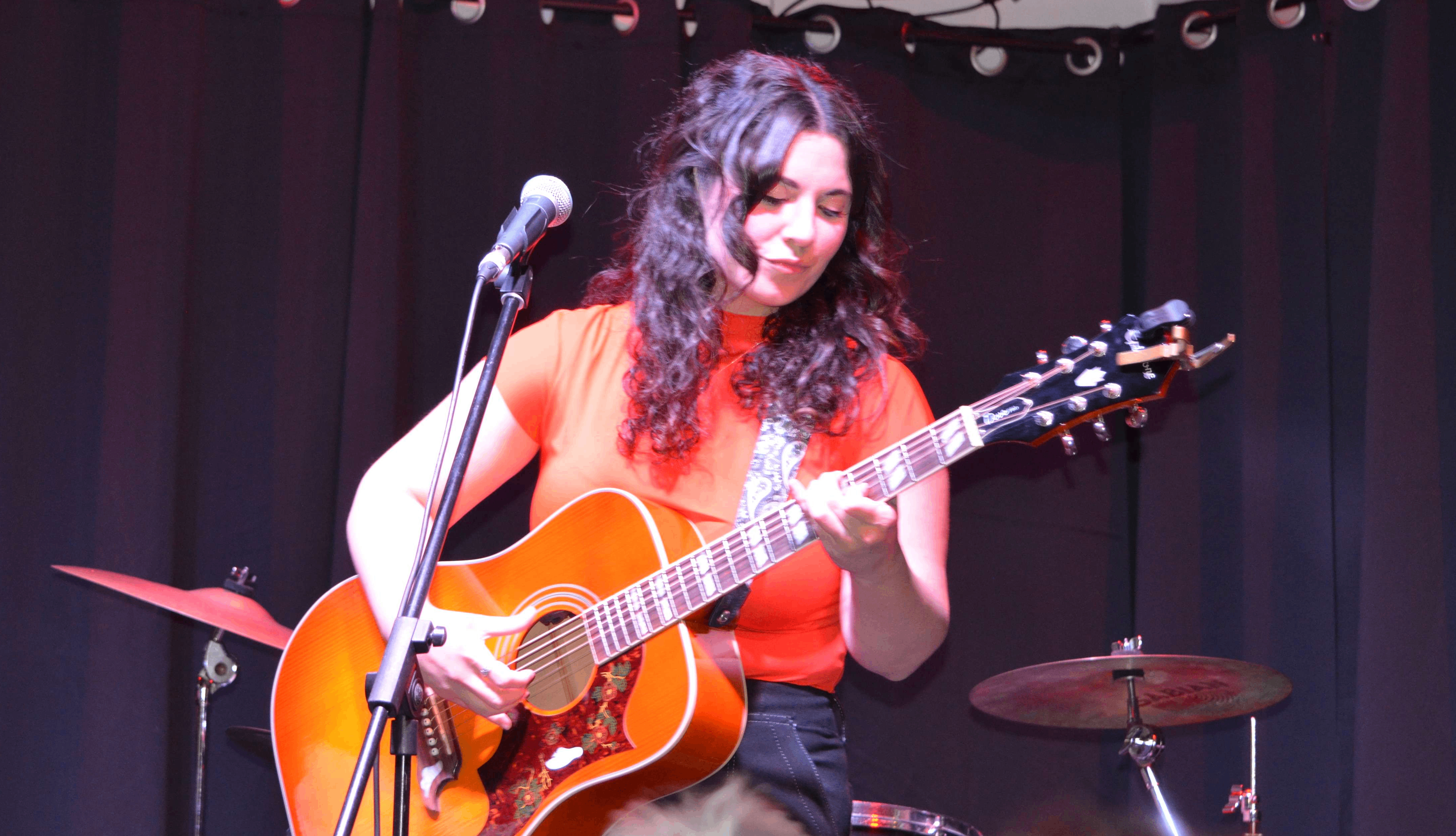 a woman playing an acoustic guitar in front of a microphone
