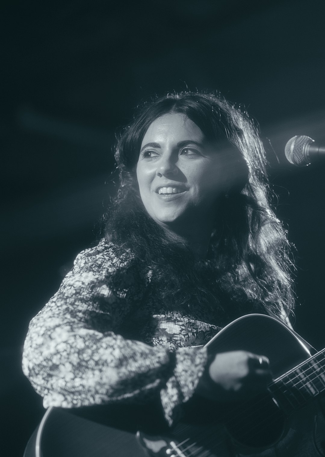 a black and white photo of a woman holding an acoustic guitar