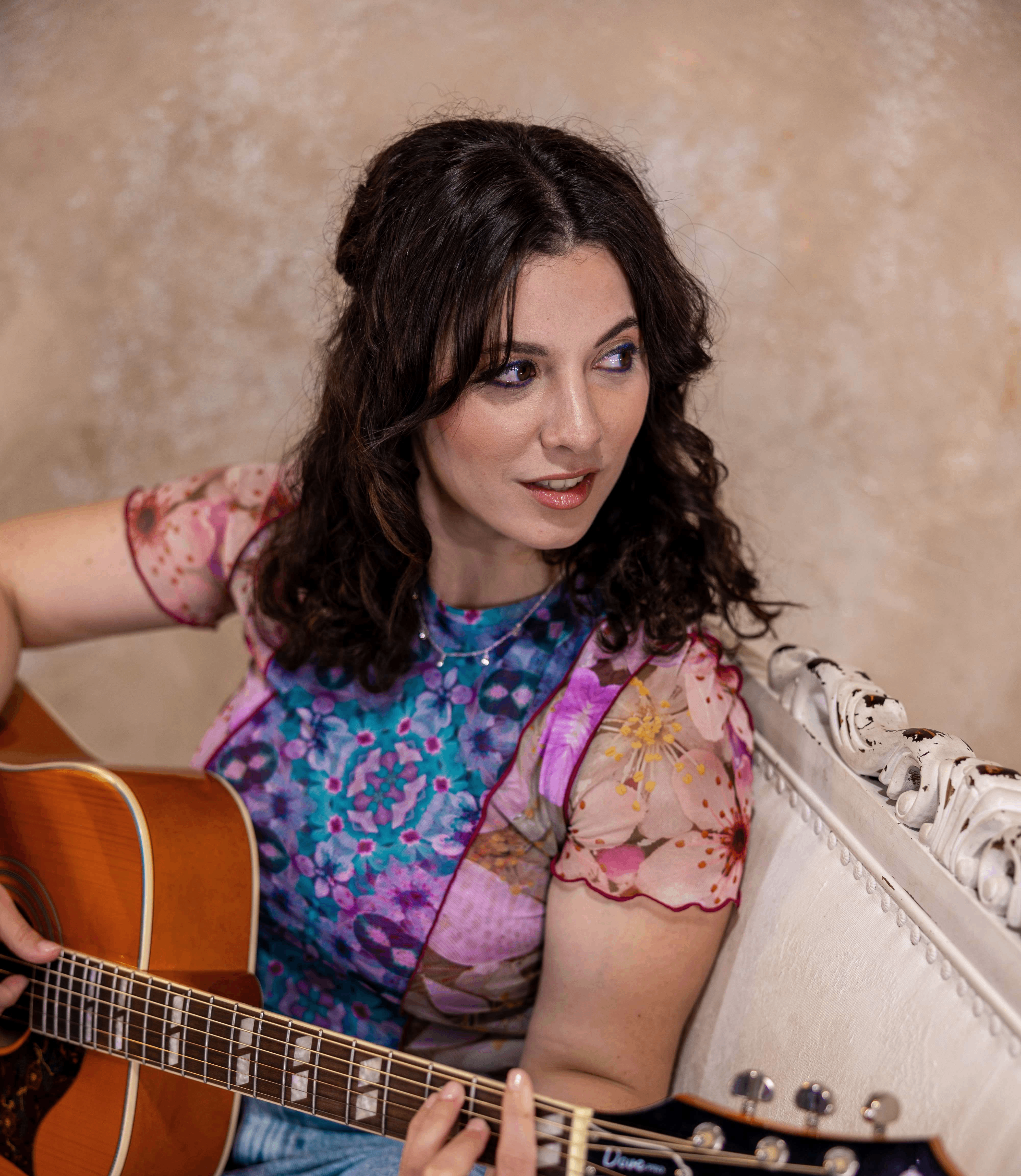 a woman sitting on a couch holding an acoustic guitar