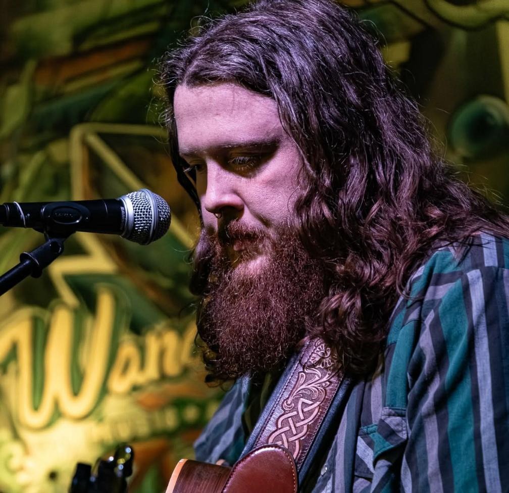a bearded man with long hair singing into a microphone
