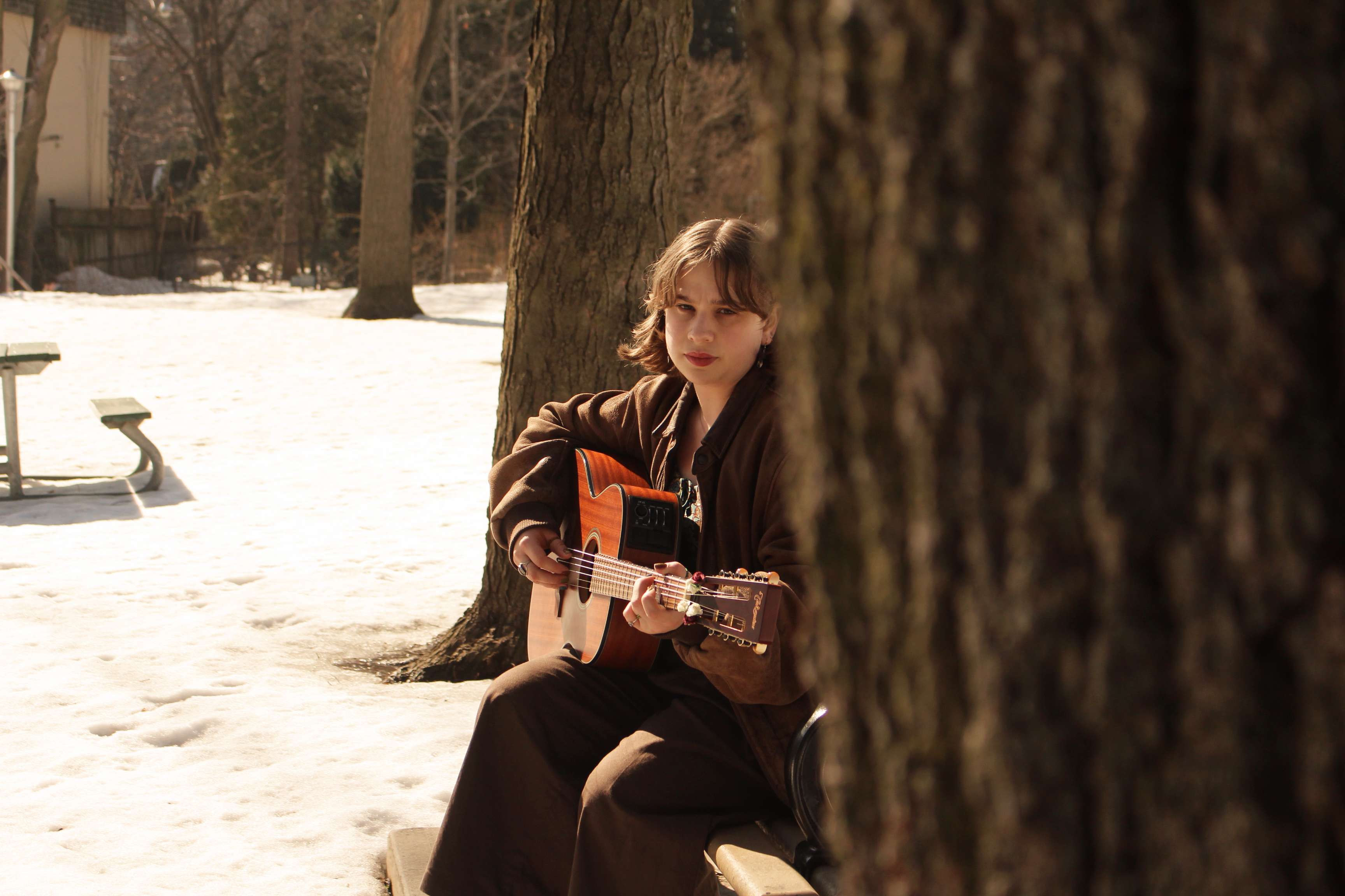 a woman sitting on a bench playing an acoustic guitar