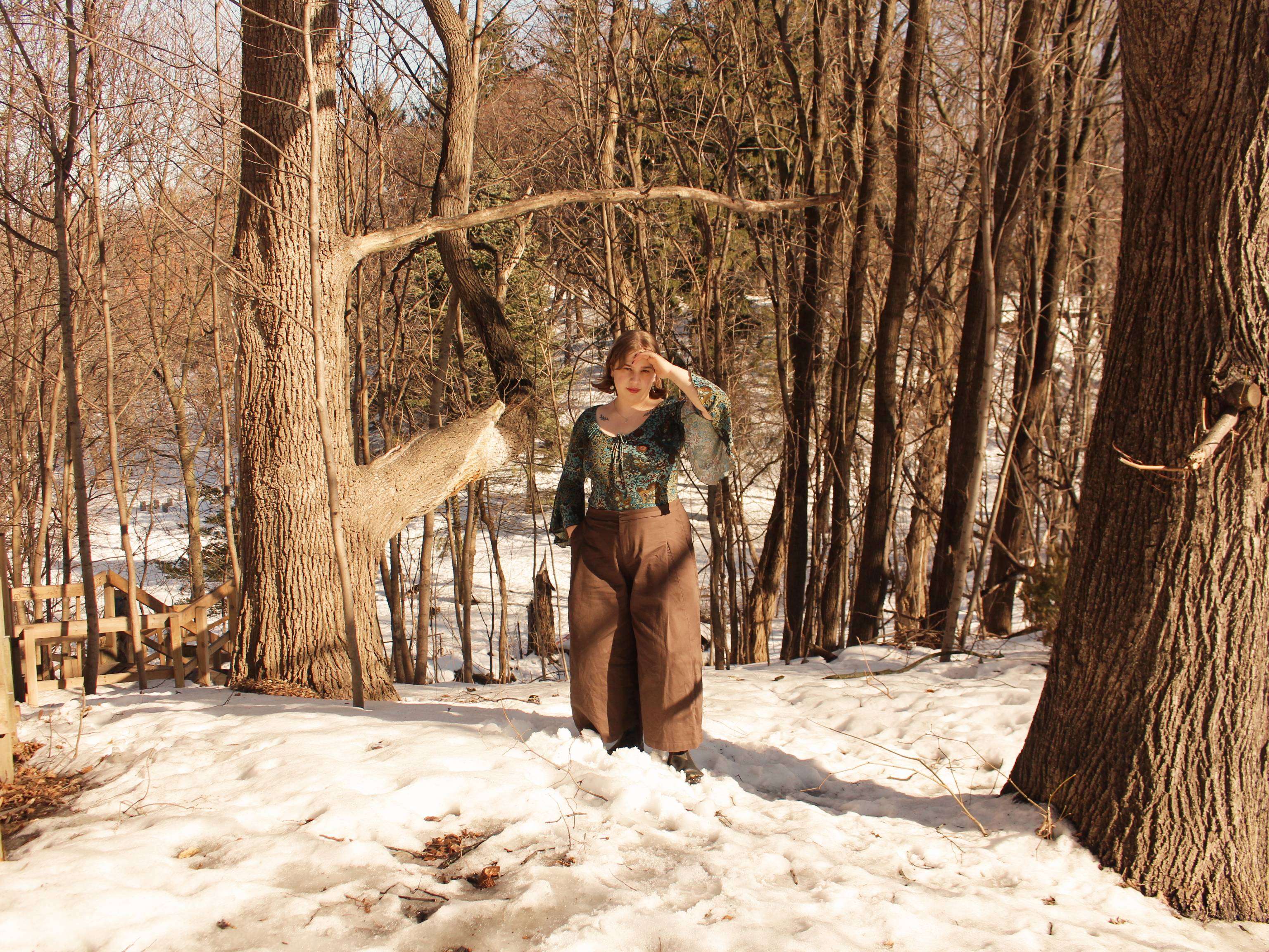 a woman standing in the snow in a wooded area