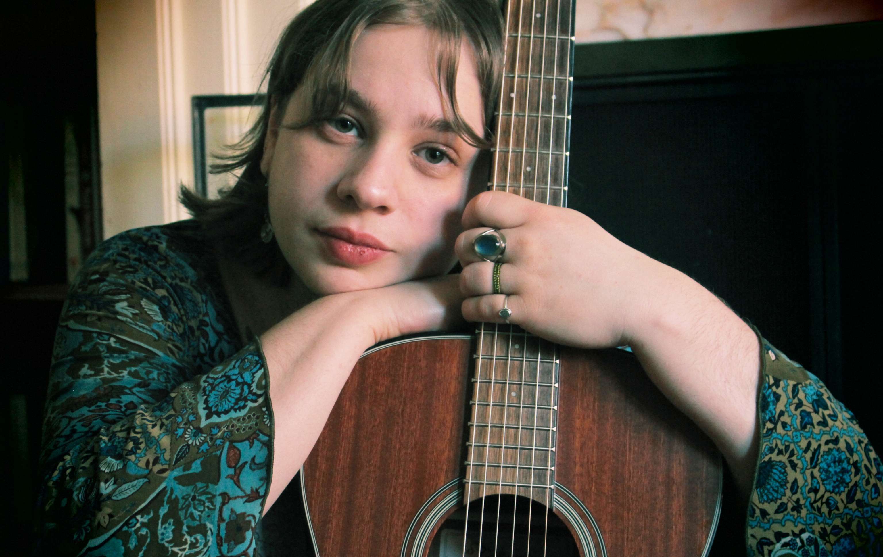 a young woman leaning against an acoustic guitar