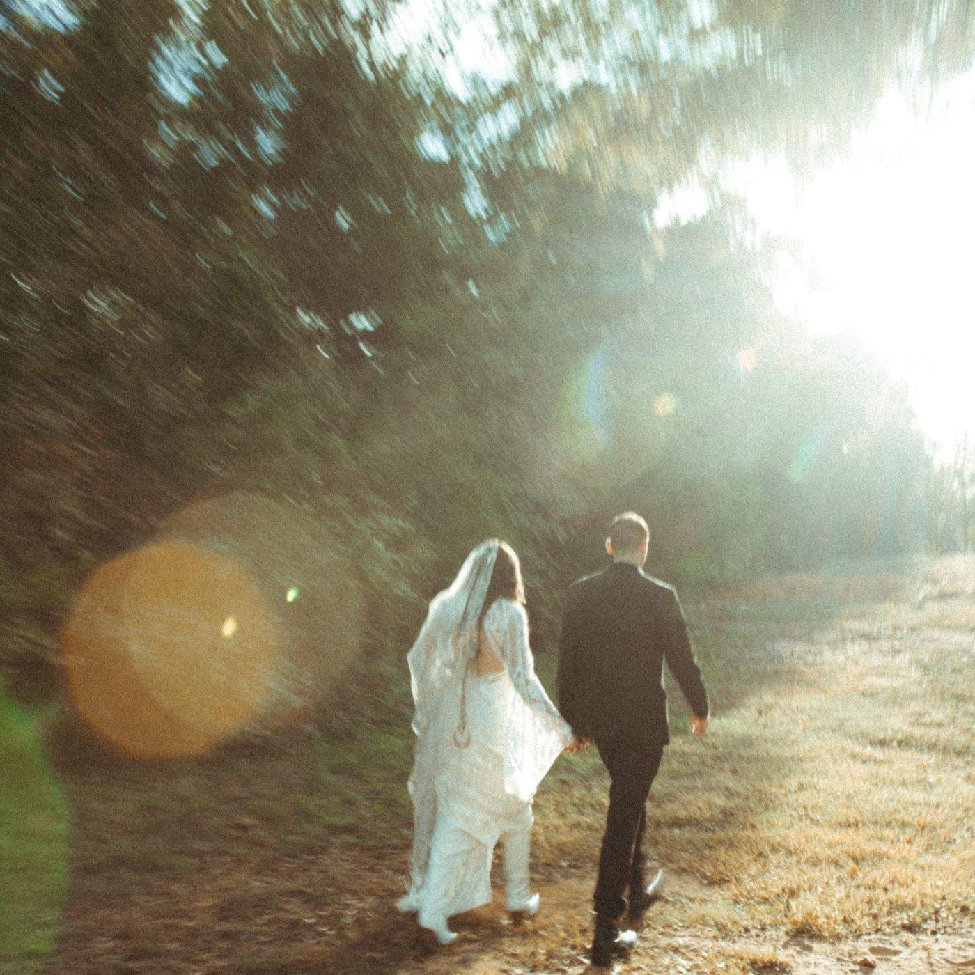 a bride and groom walking down a path