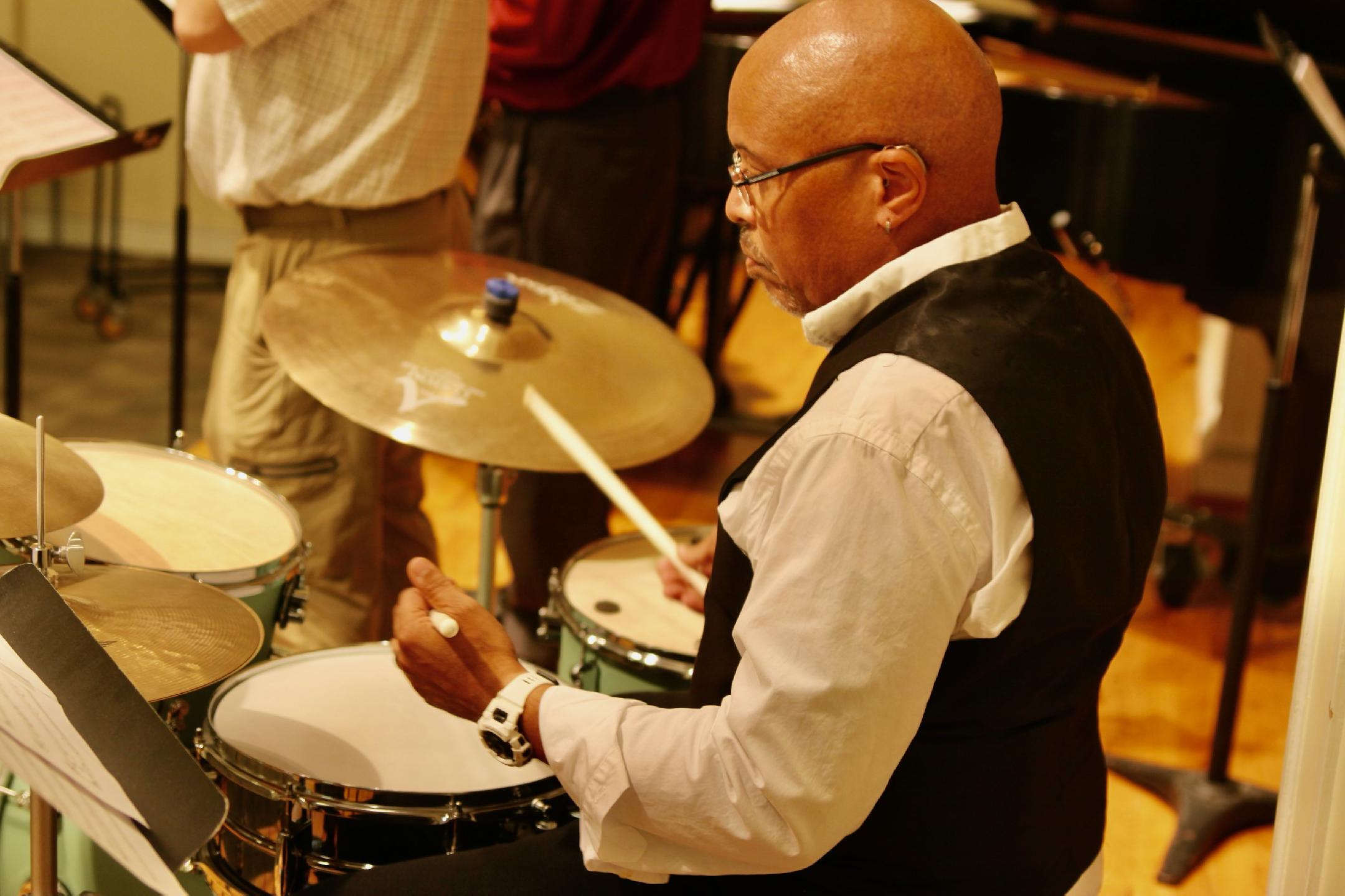 a man playing drums in a room with other musicians