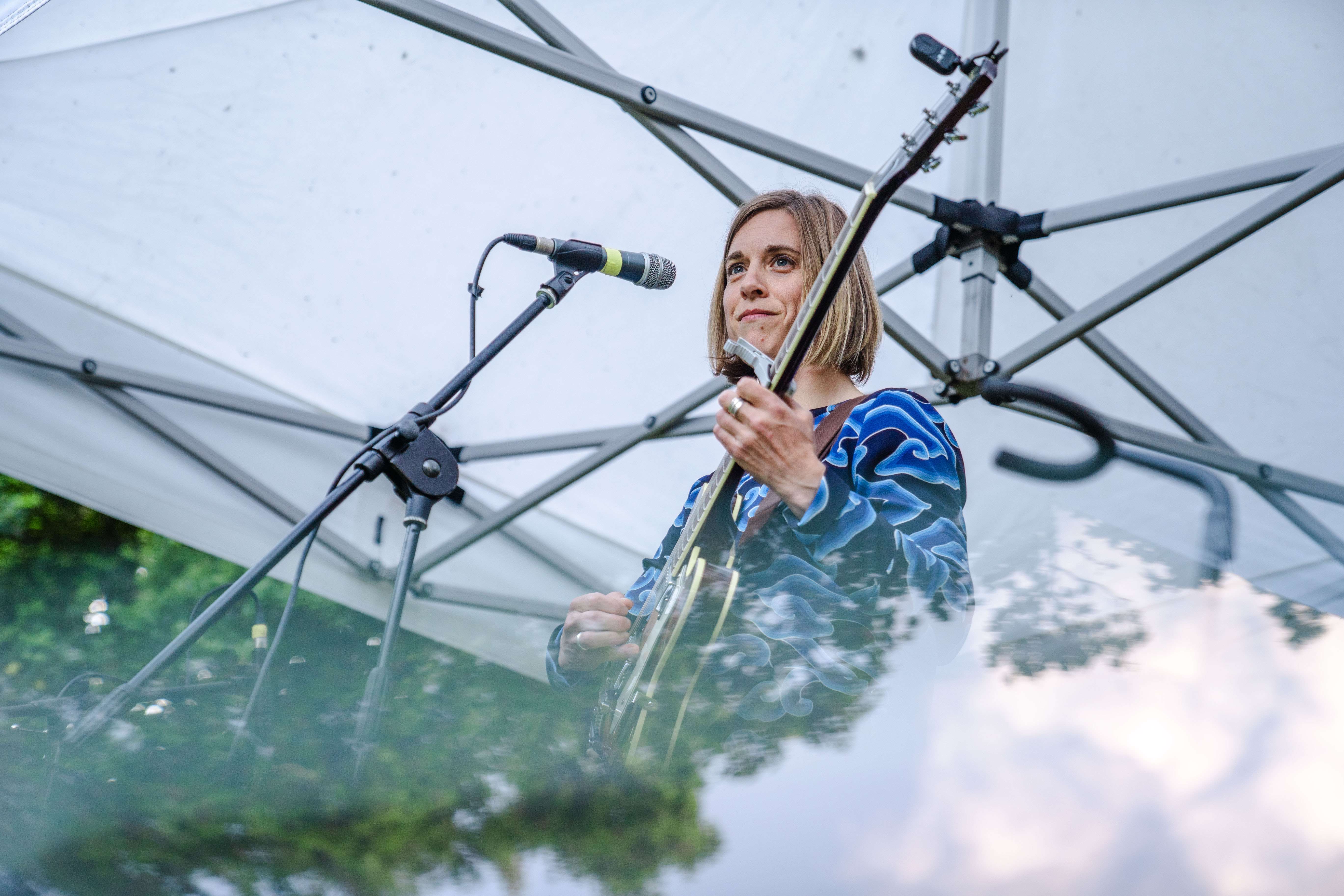 a woman playing a guitar in front of a microphone