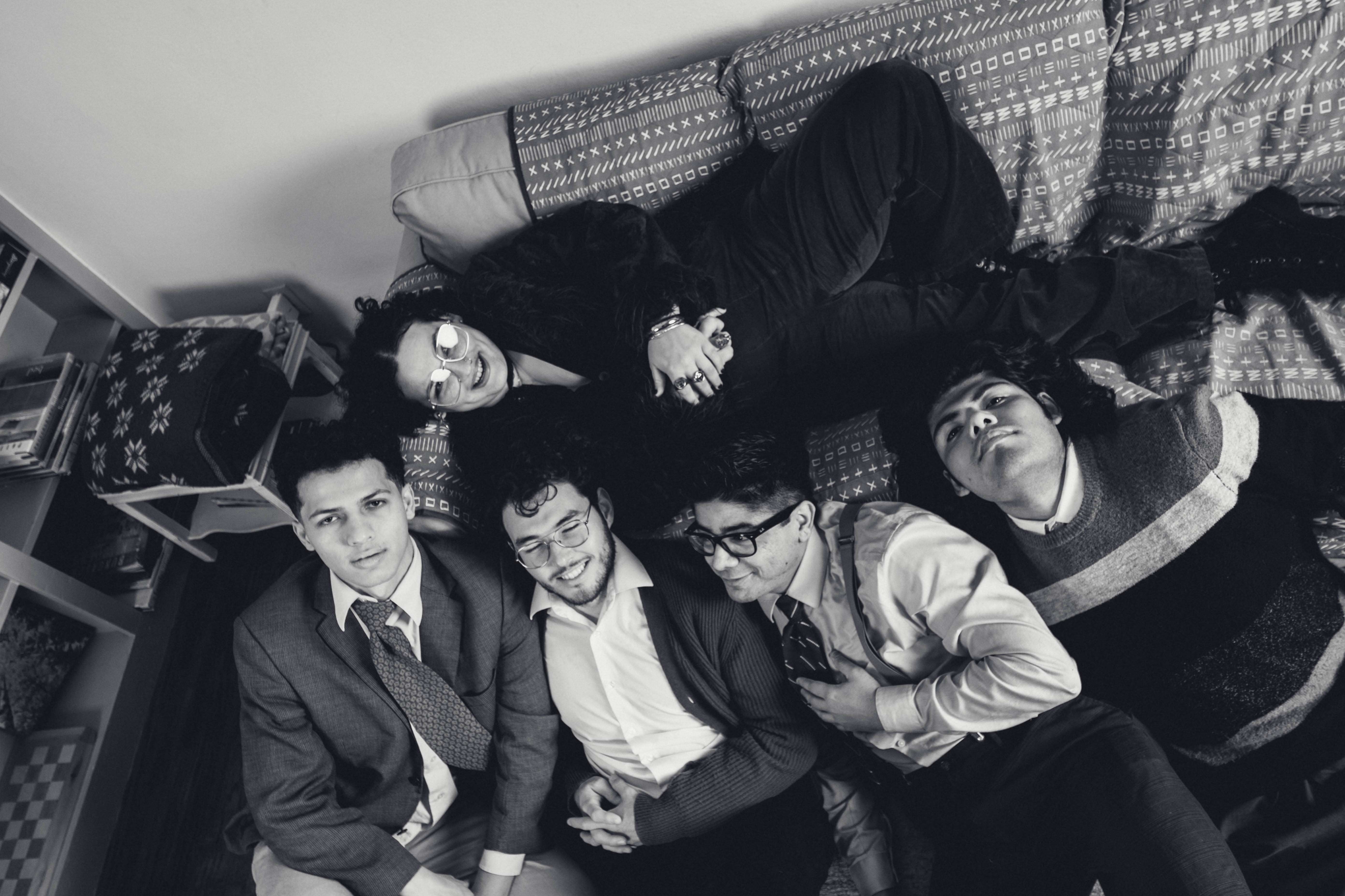 a black and white photo of a group of people laying on a couch