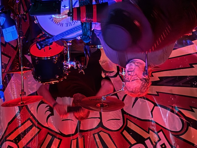 a man in a hat is playing drums on a stage