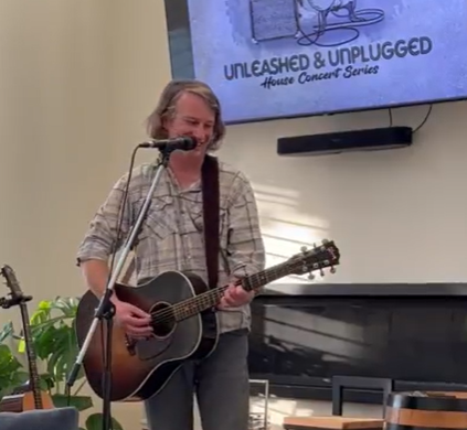 a man playing an acoustic guitar in front of a television