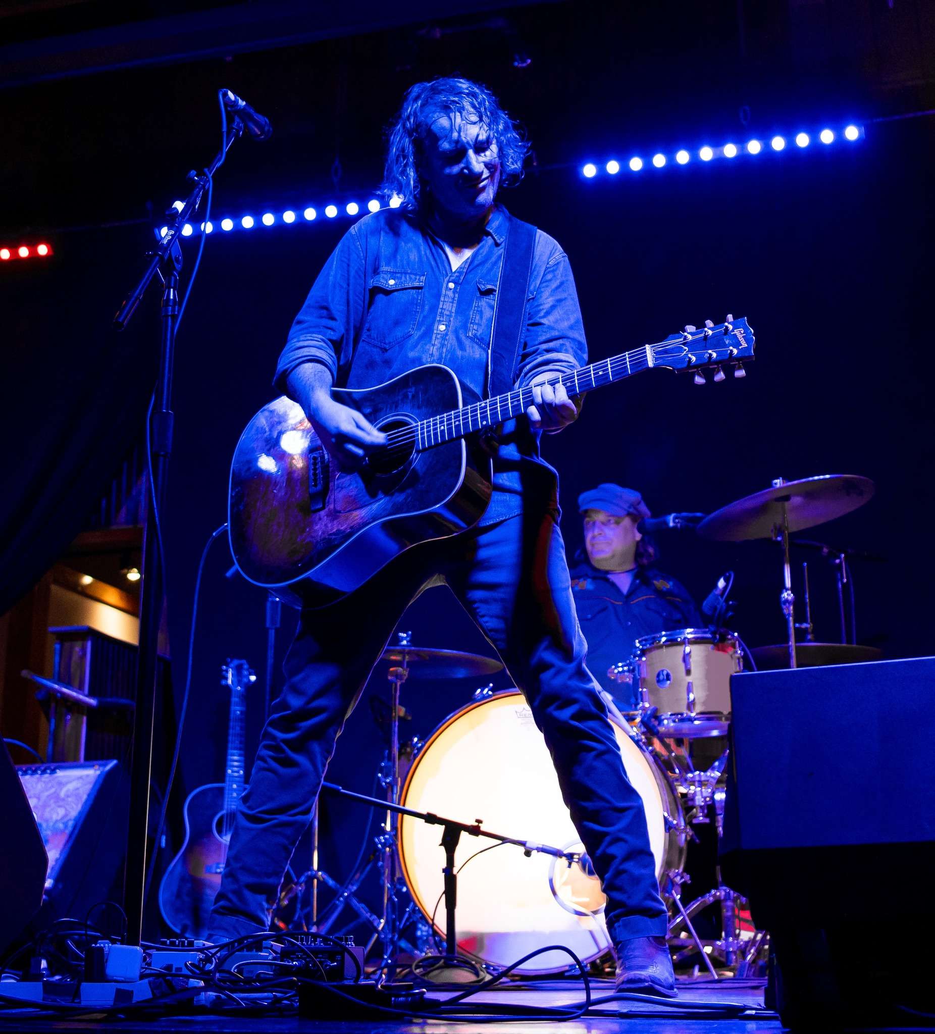 a man playing an acoustic guitar on stage