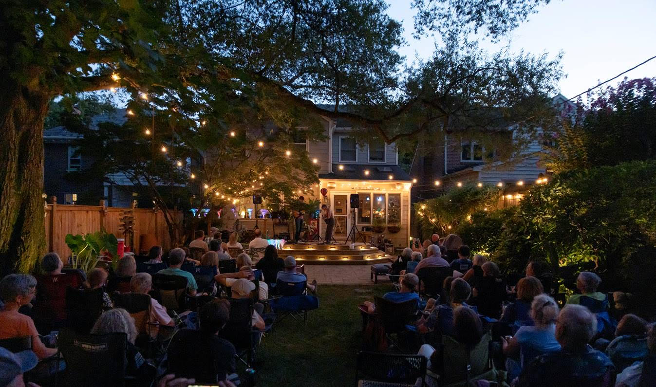 a group of people sitting in a backyard at dusk