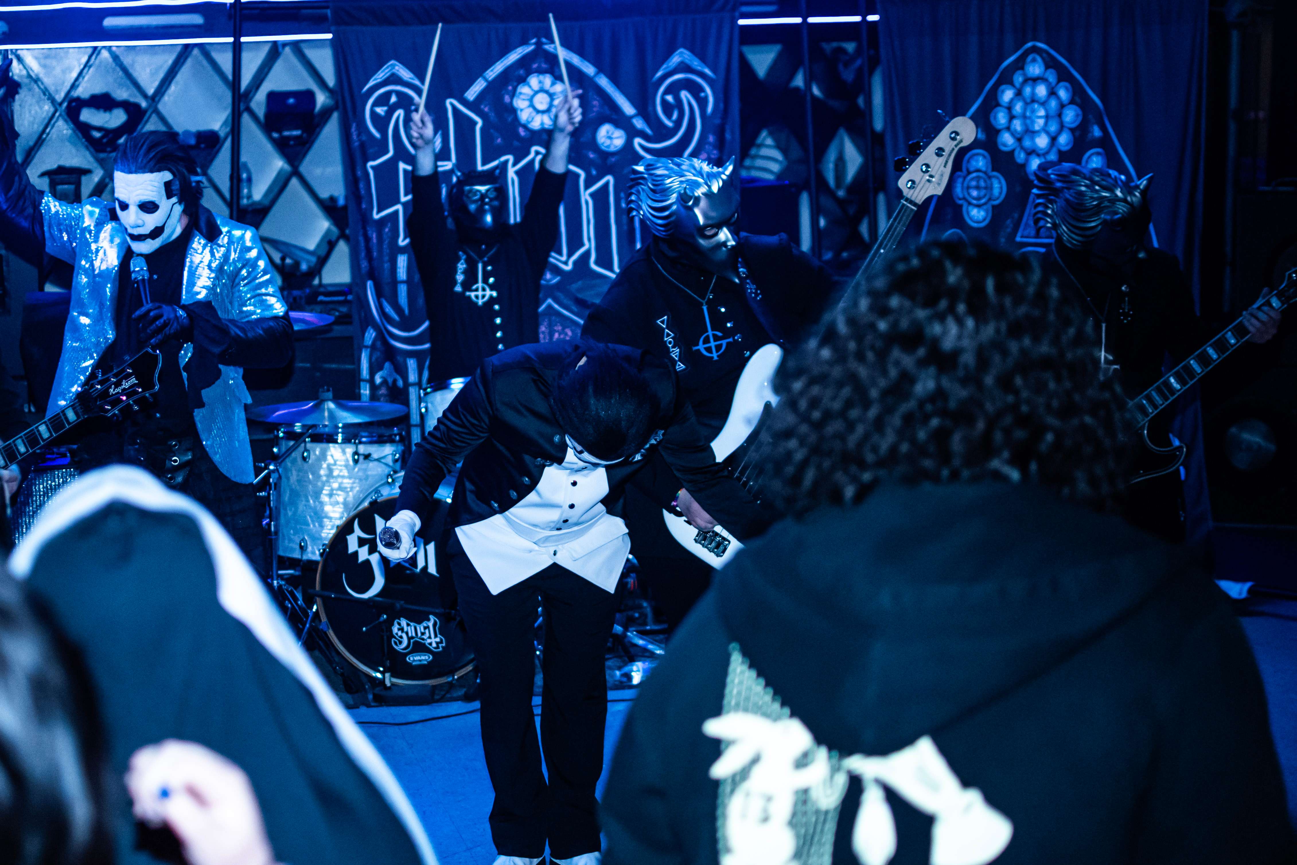 a group of people in black hooded shirts standing in front of a stage