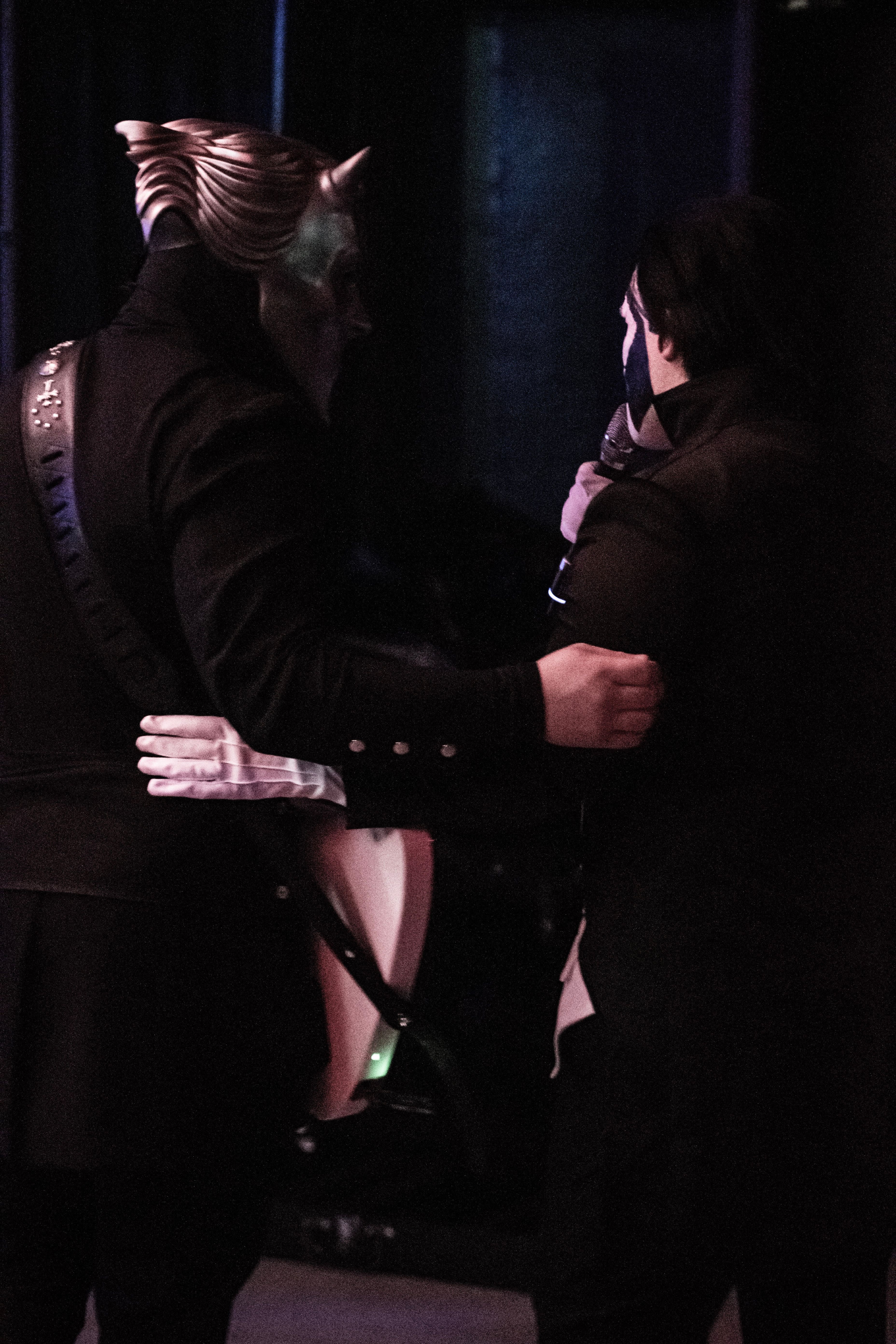 two men in black costumes hugging each other on stage