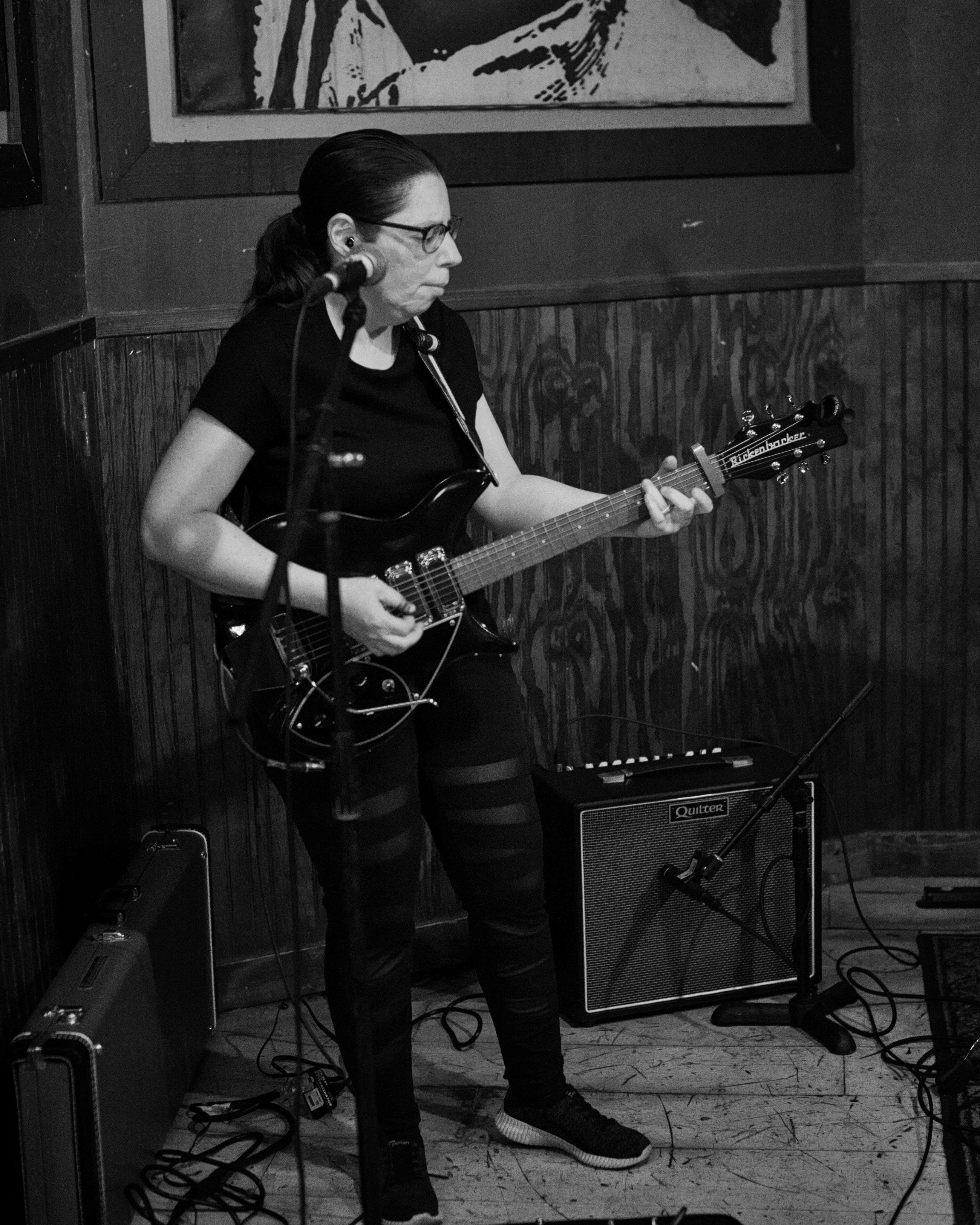 a black and white photo of a woman playing an electric guitar