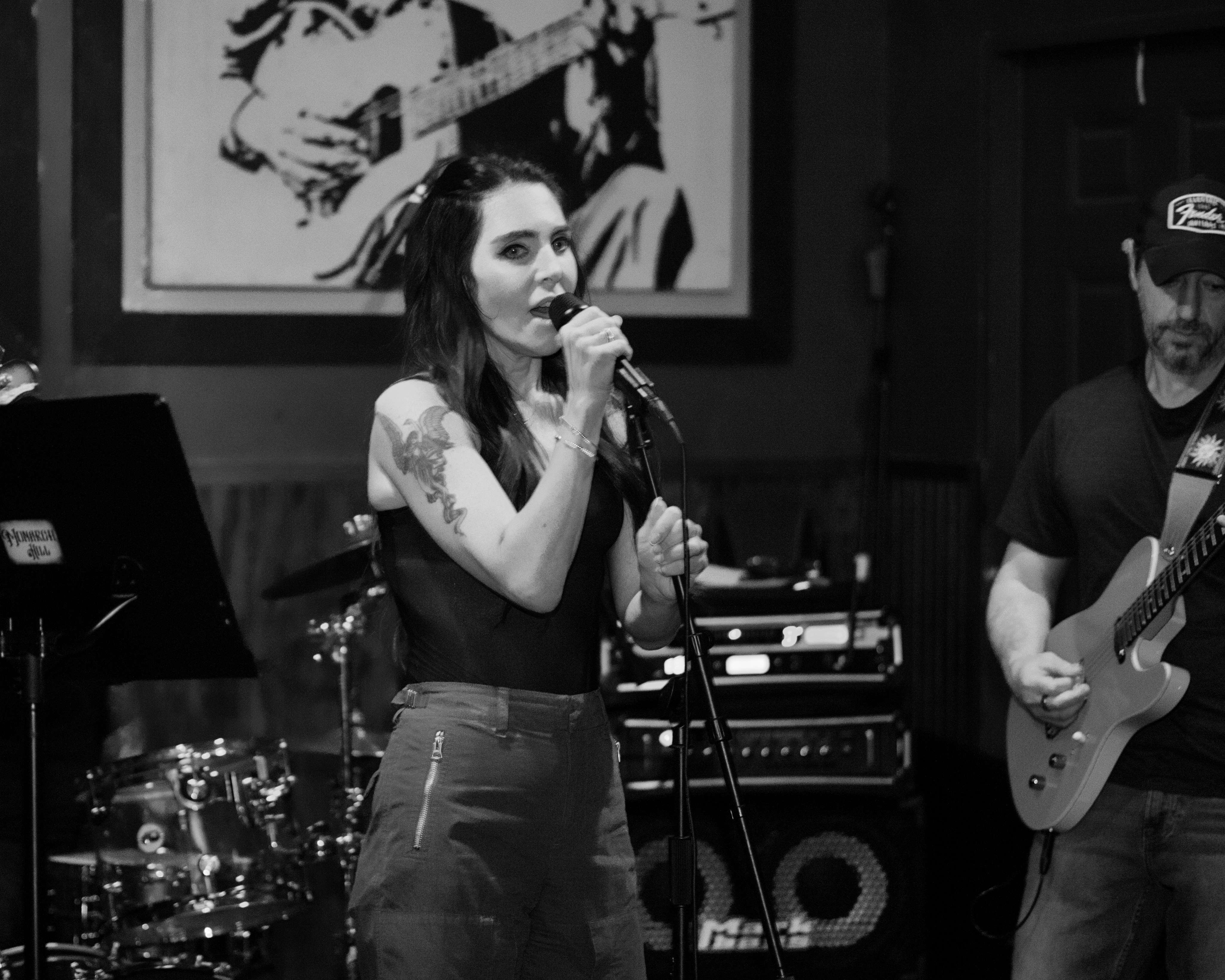 a woman singing and playing a guitar in front of a band