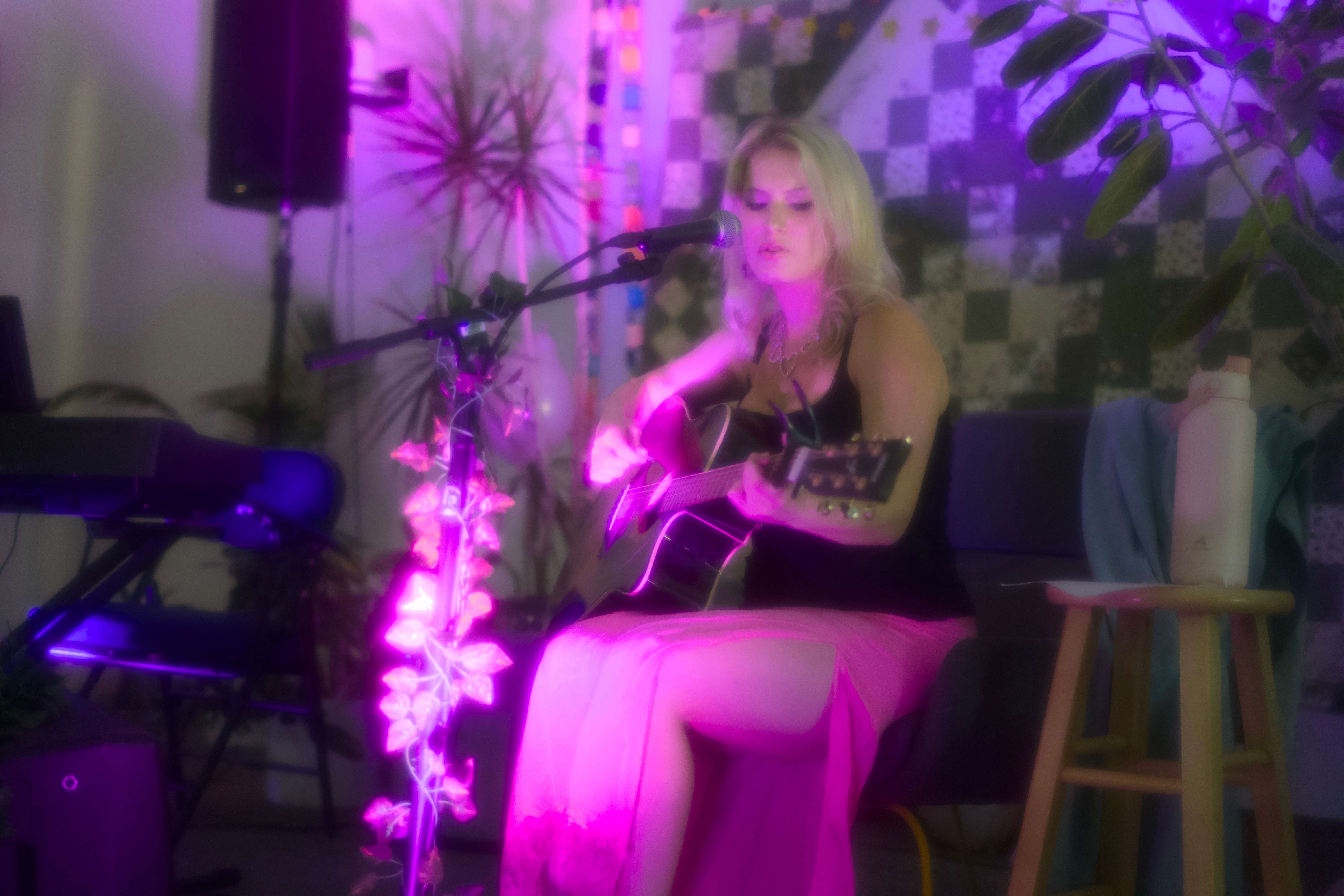 a woman in a pink dress playing an acoustic guitar