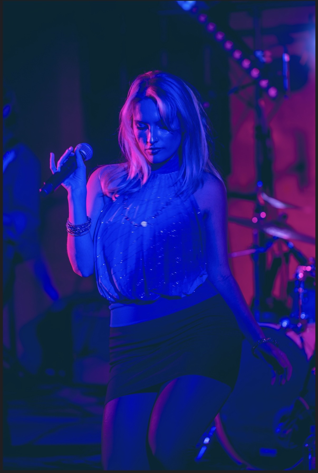 a woman in a blue dress singing into a microphone