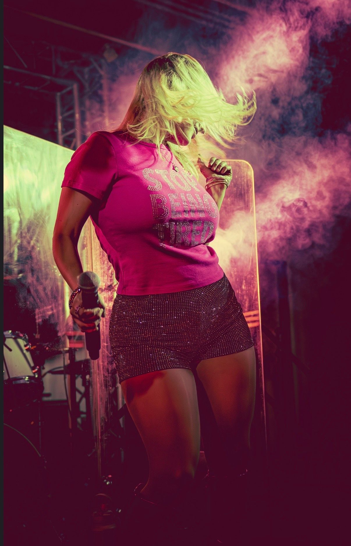 a woman in a pink t-shirt singing into a microphone