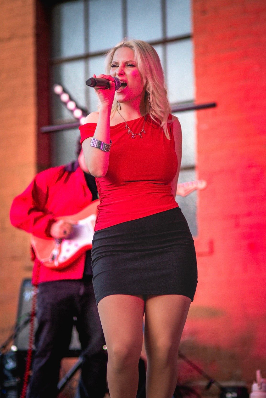 a woman in a red top singing into a microphone