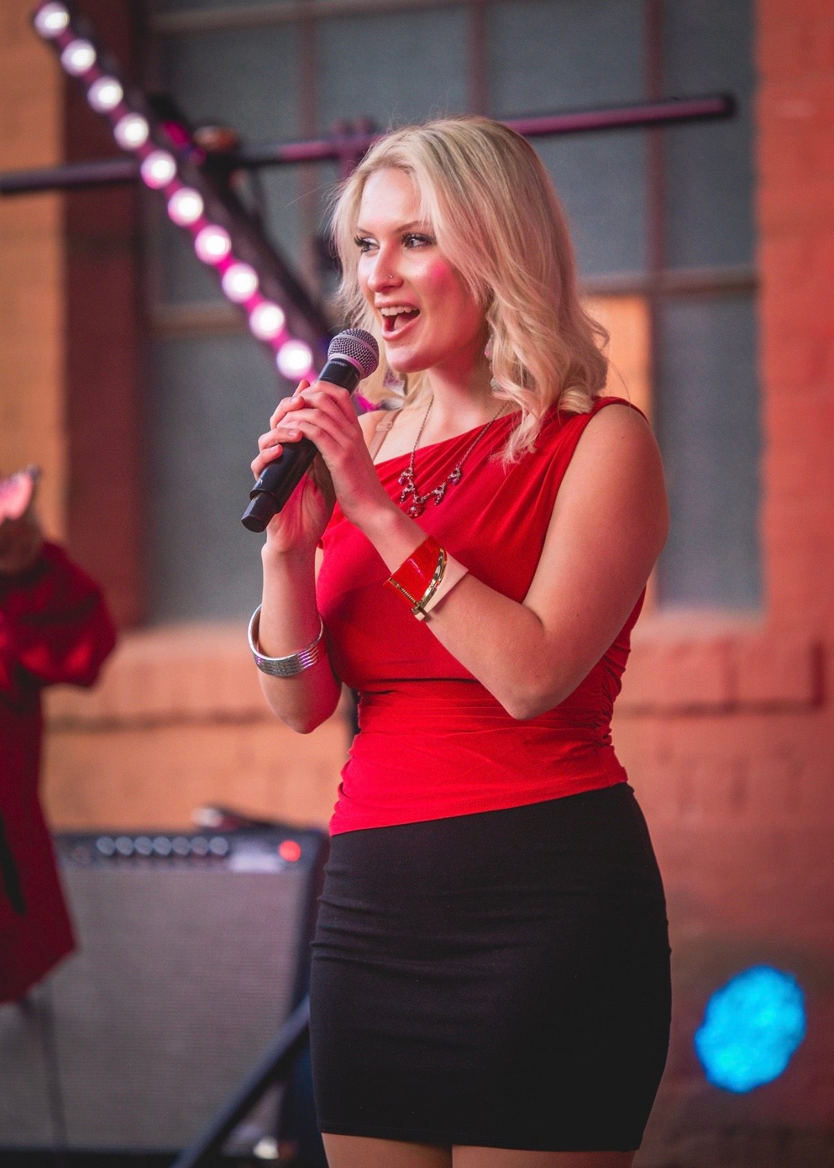 a woman in a red dress singing into a microphone