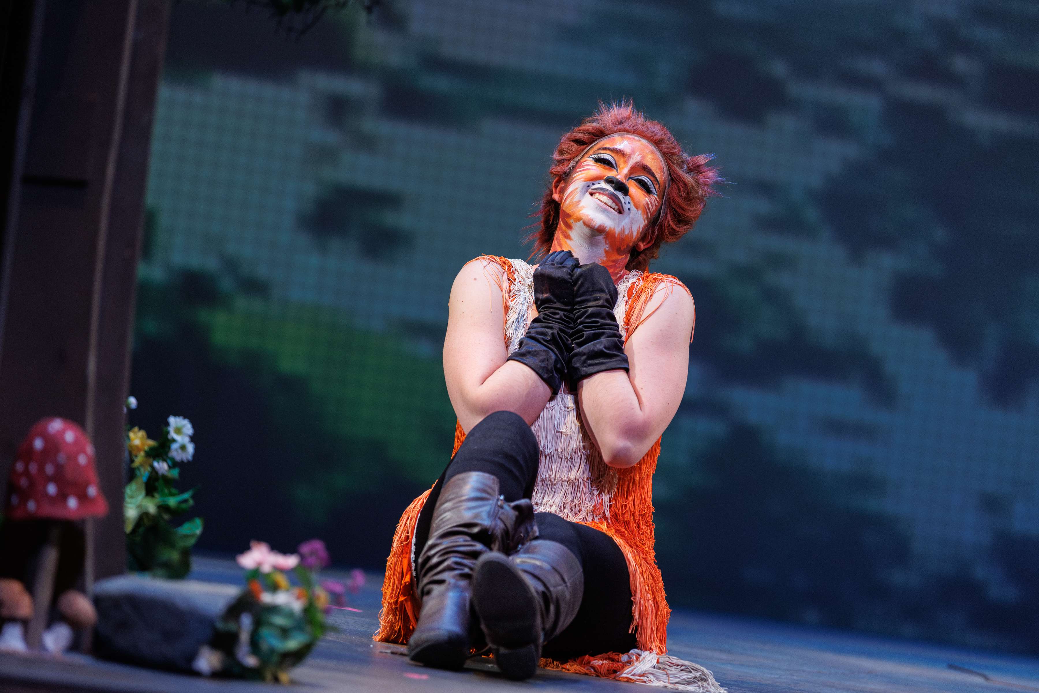 a woman sitting on stage with a mask on her face