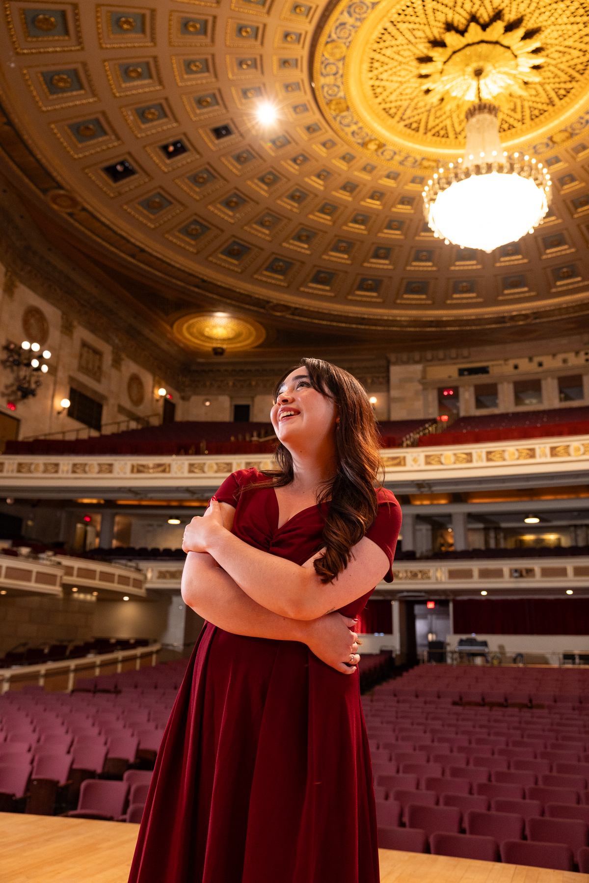 a young woman in a red dress standing in a large auditorium