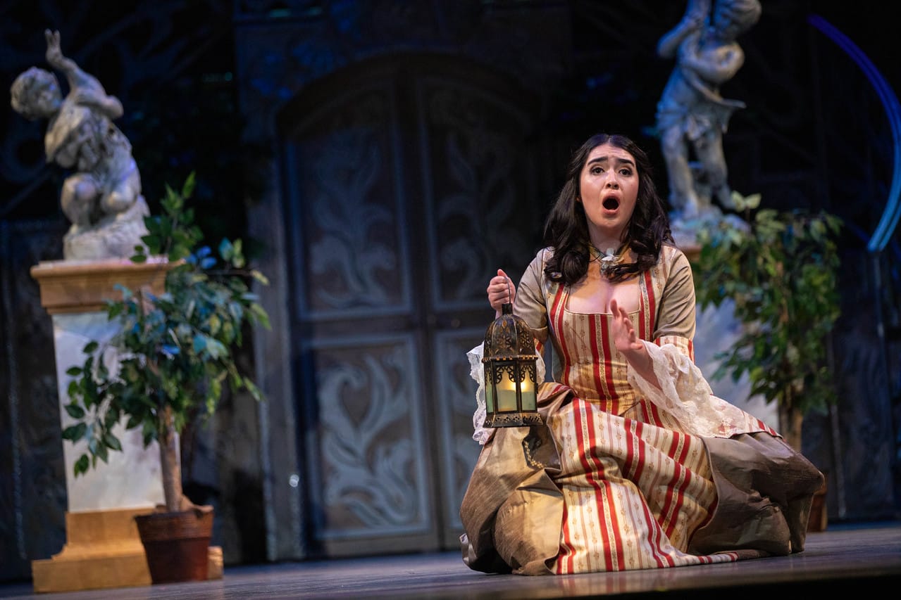 a woman in a costume on stage holding a lantern
