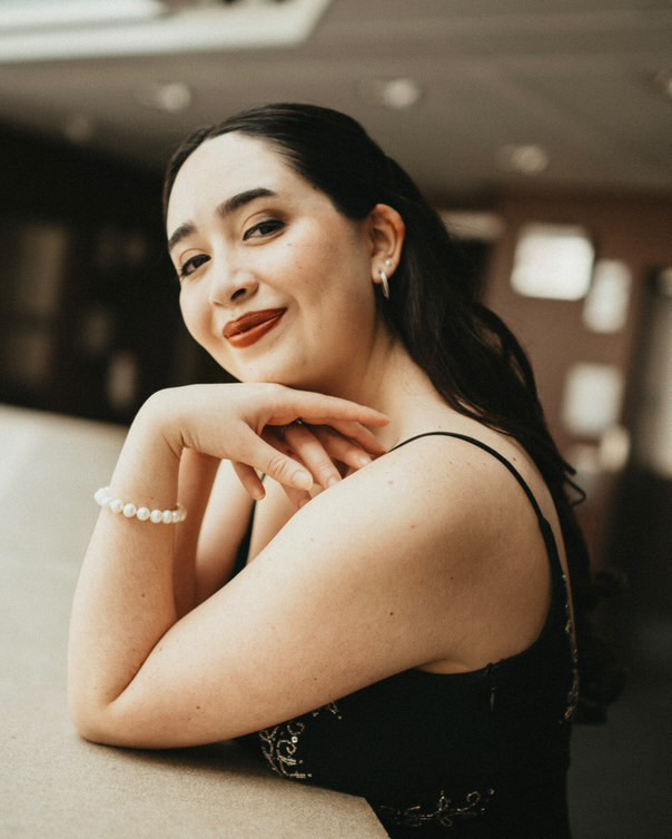 a woman in a black dress leaning on a table