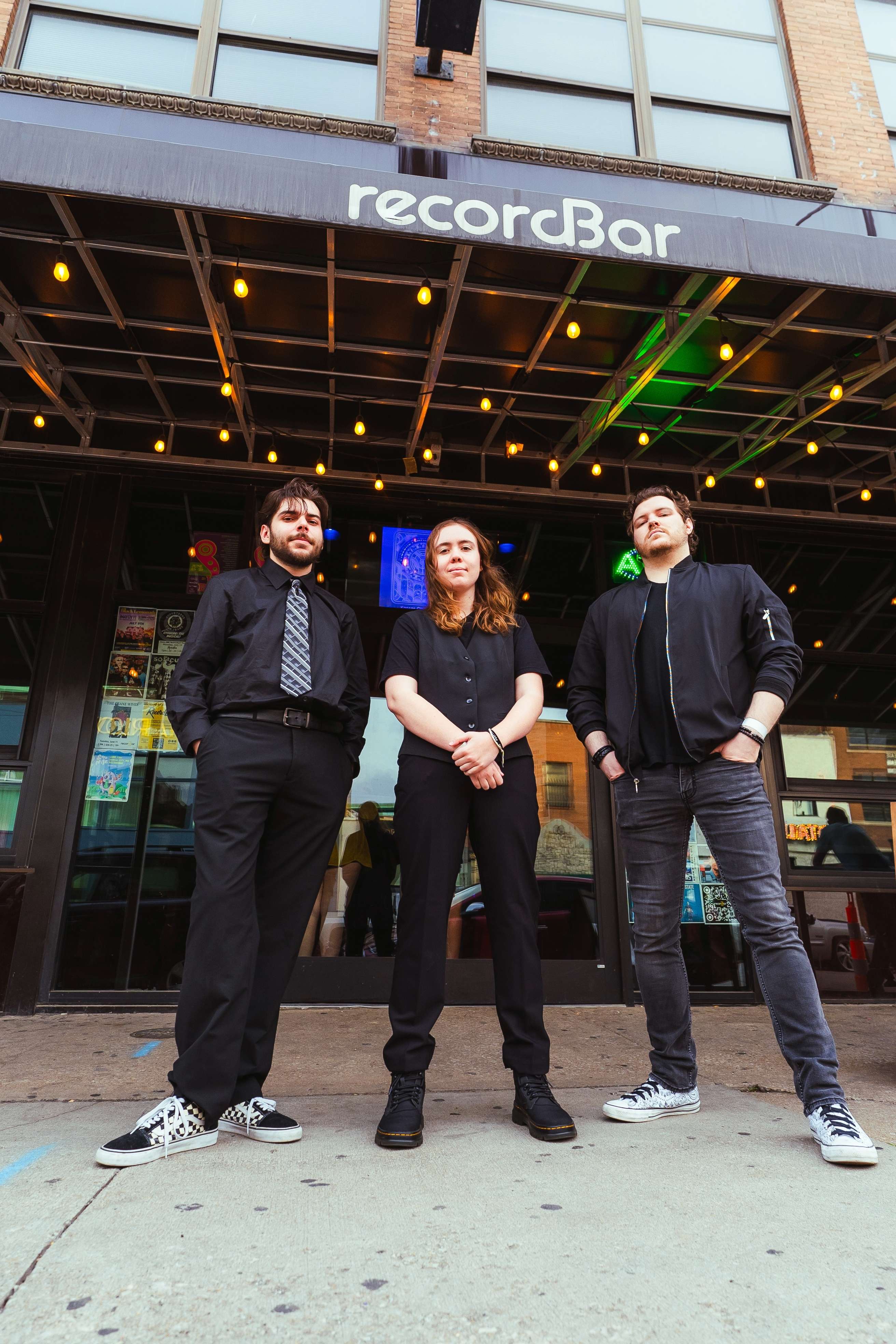 three men standing in front of a record bar